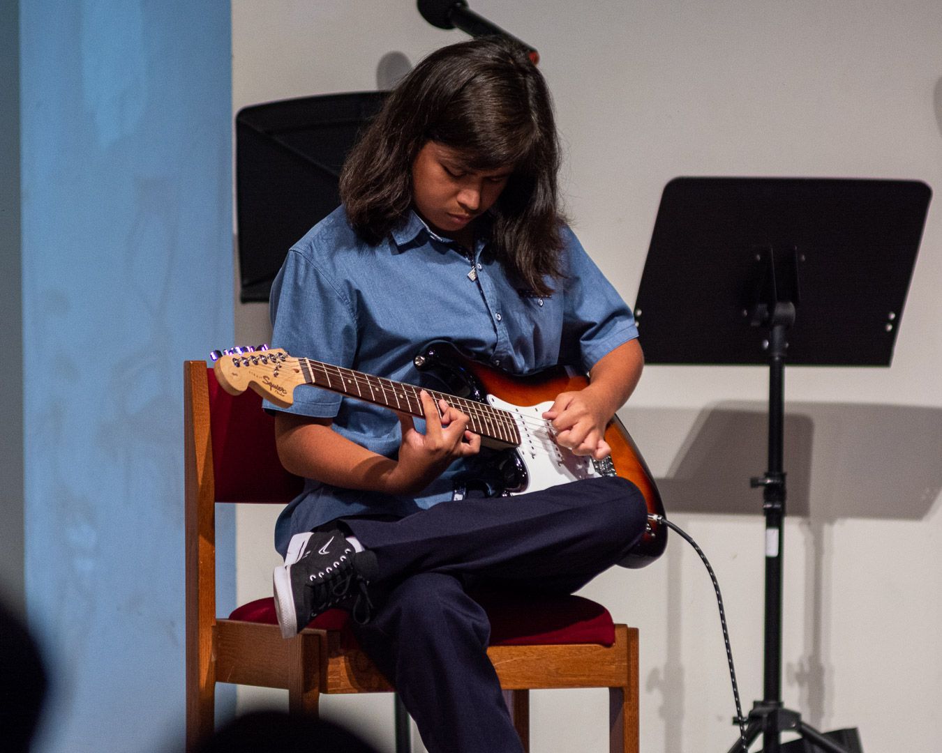 A woman is sitting in a chair playing an electric guitar
