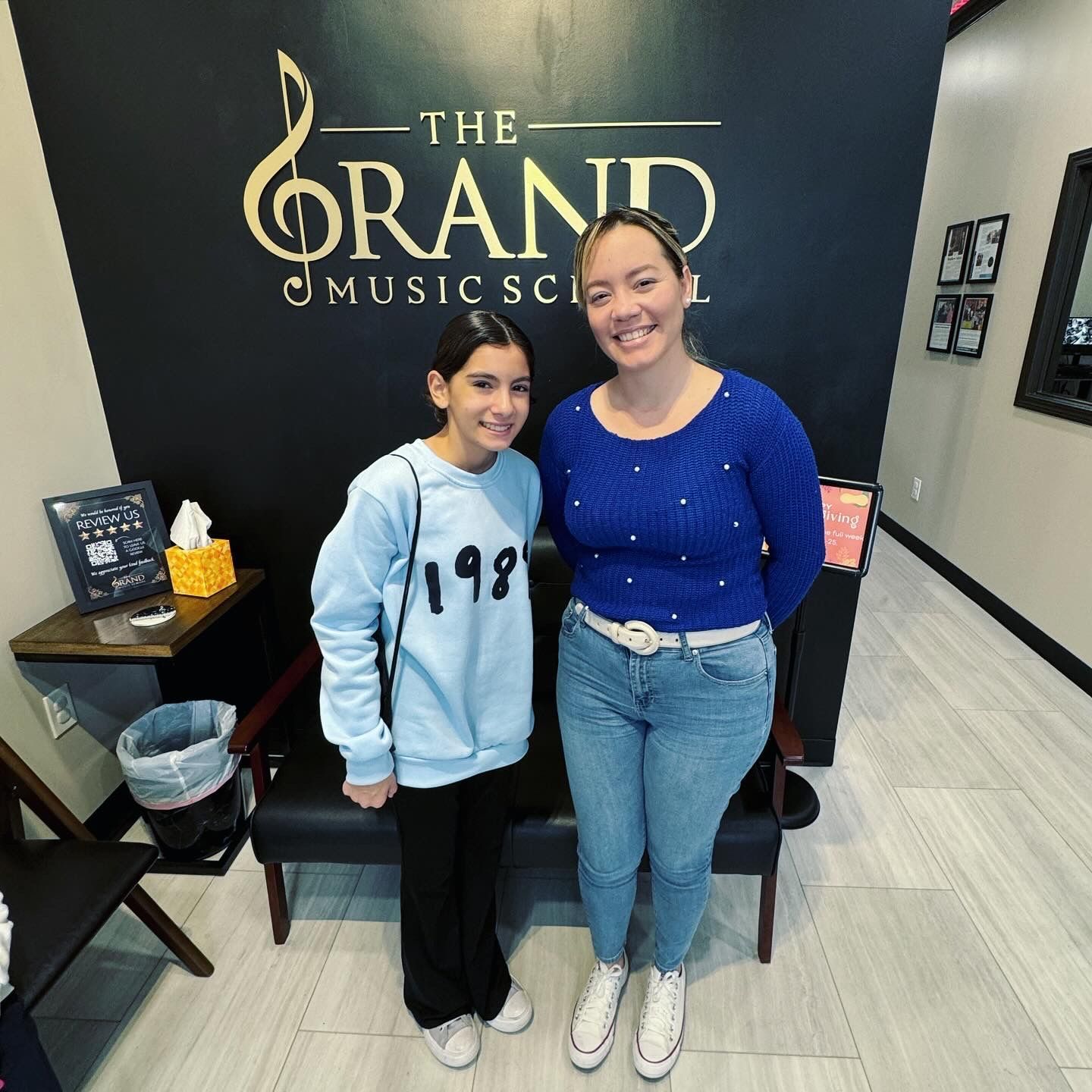 Two women standing in front of a sign that says the grand music school
