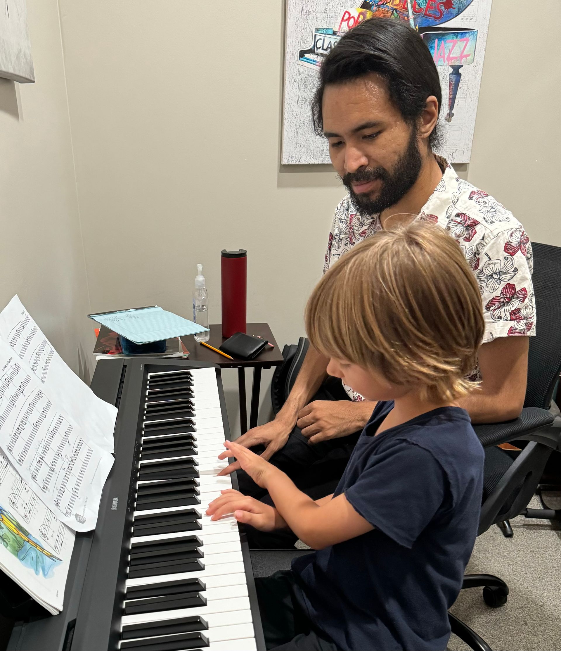 A man is teaching a young boy how to play the piano.