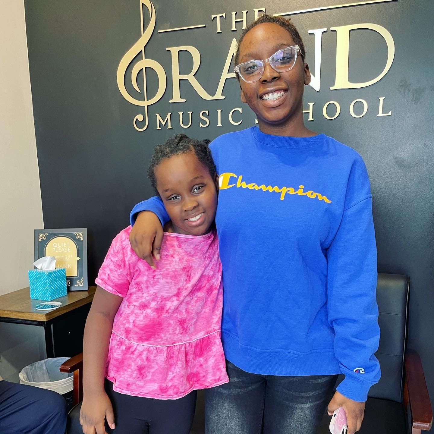 A woman in a blue champion sweatshirt stands next to a little girl