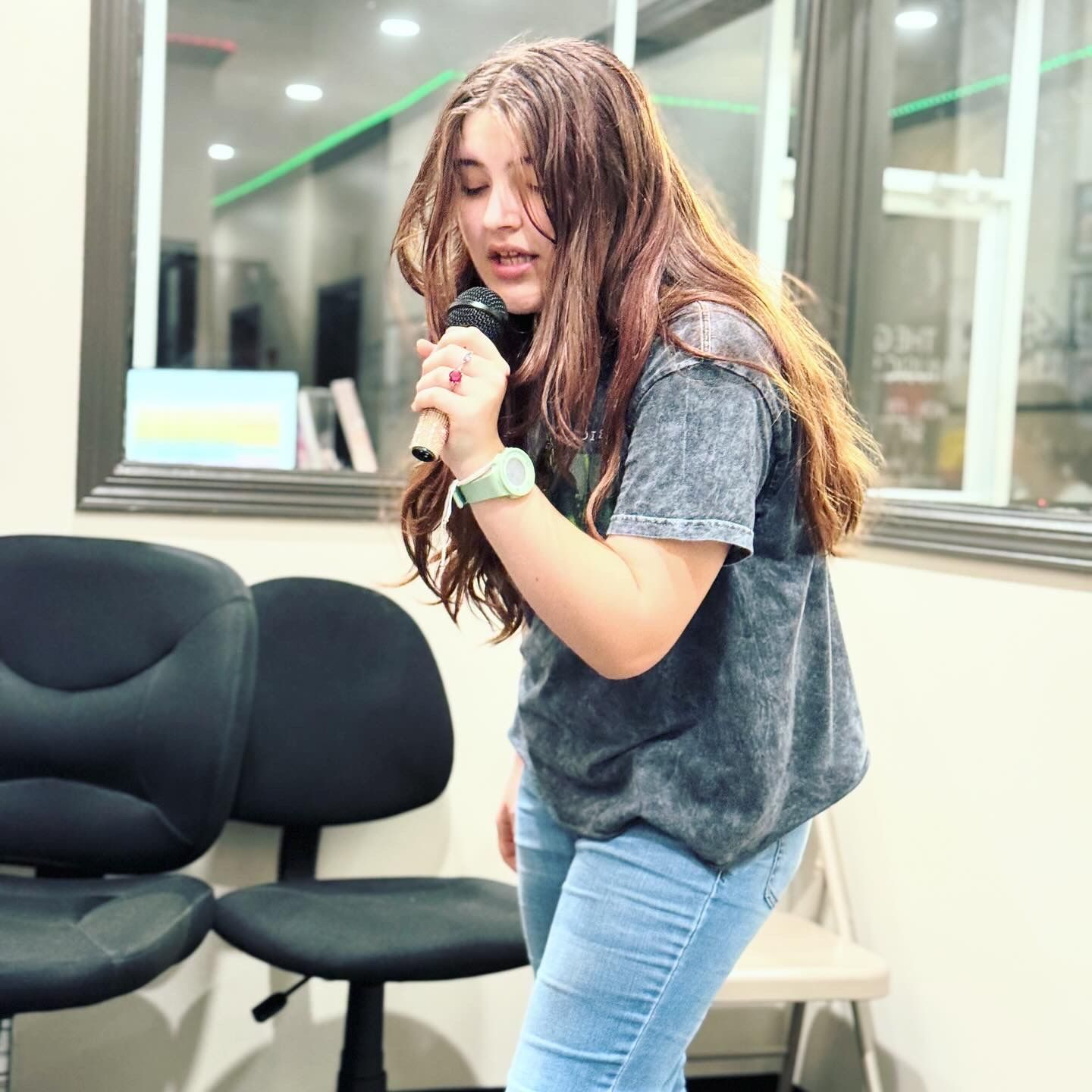 A girl is singing into a microphone in a room