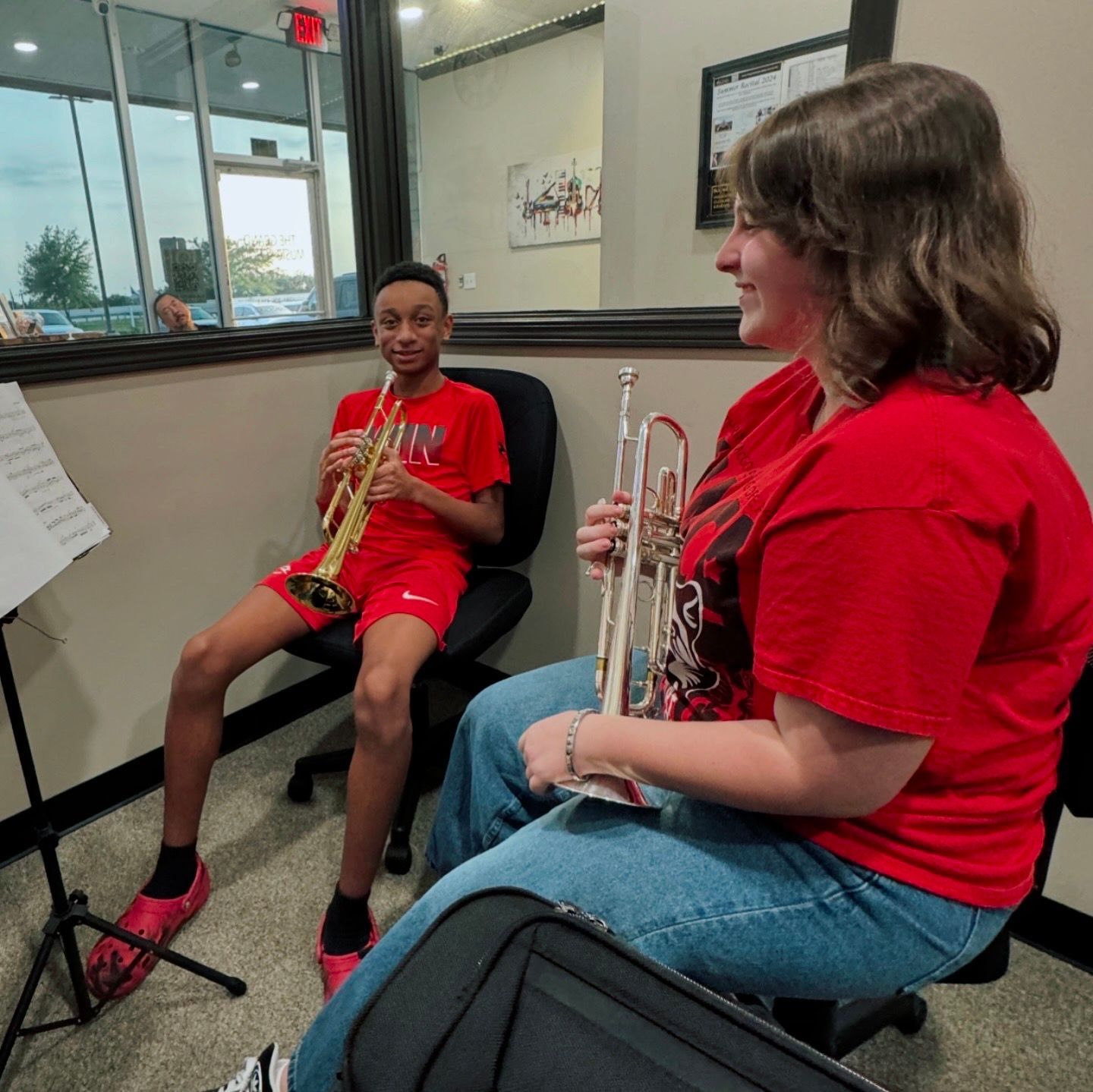 A woman is sitting next to a boy playing a trumpet.