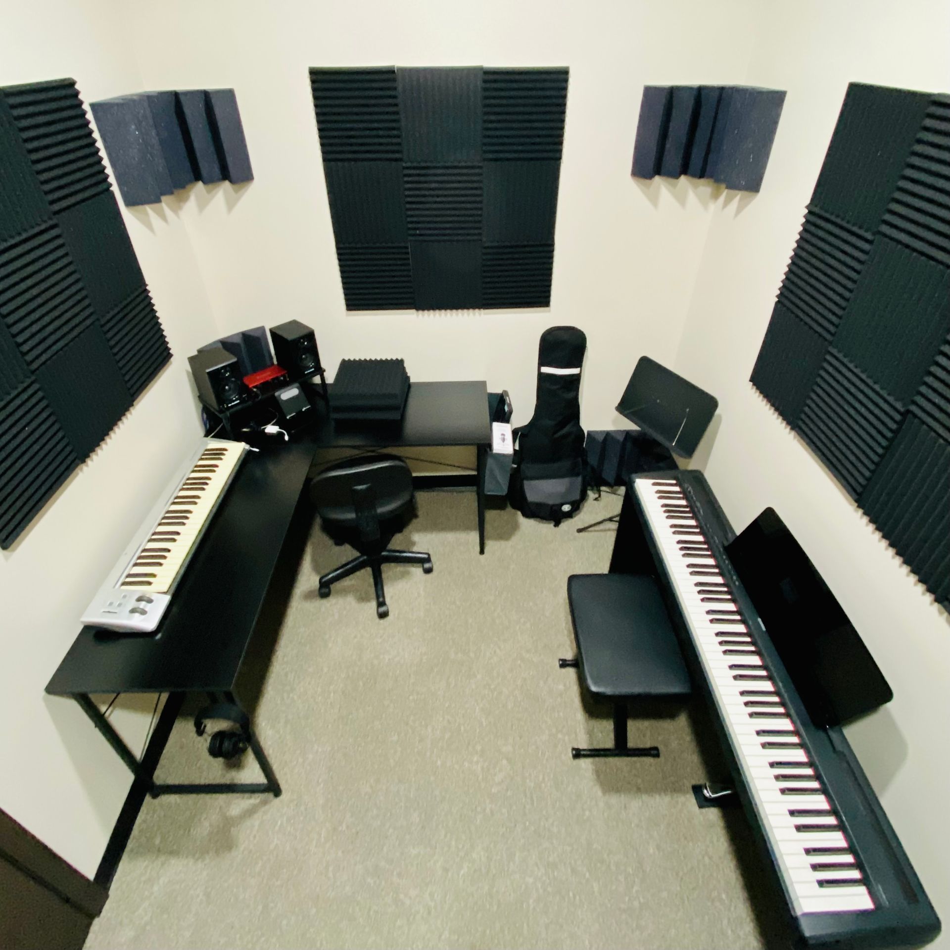 A room with two keyboards and a stool