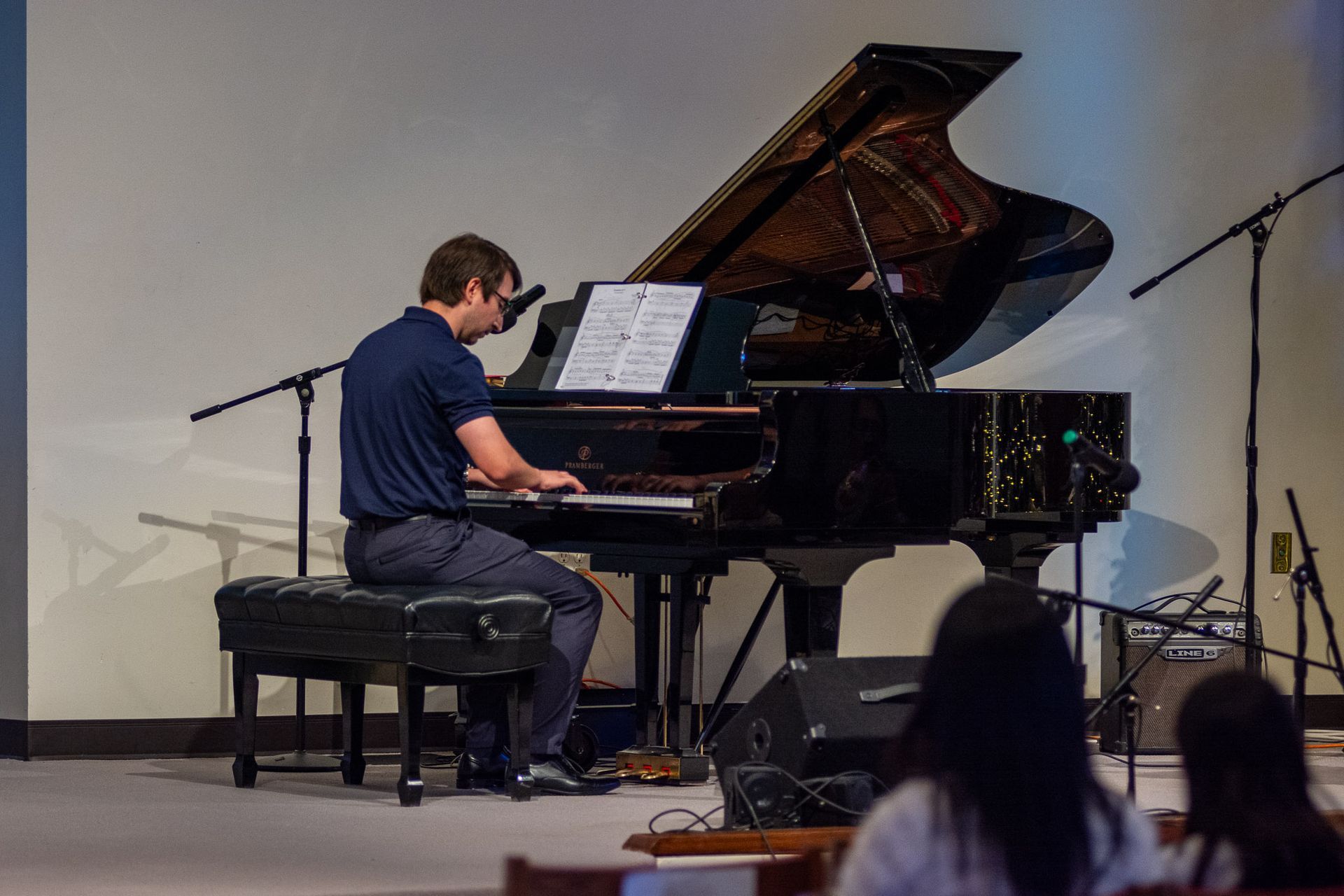 A man is playing a piano on a stage in front of a crowd.