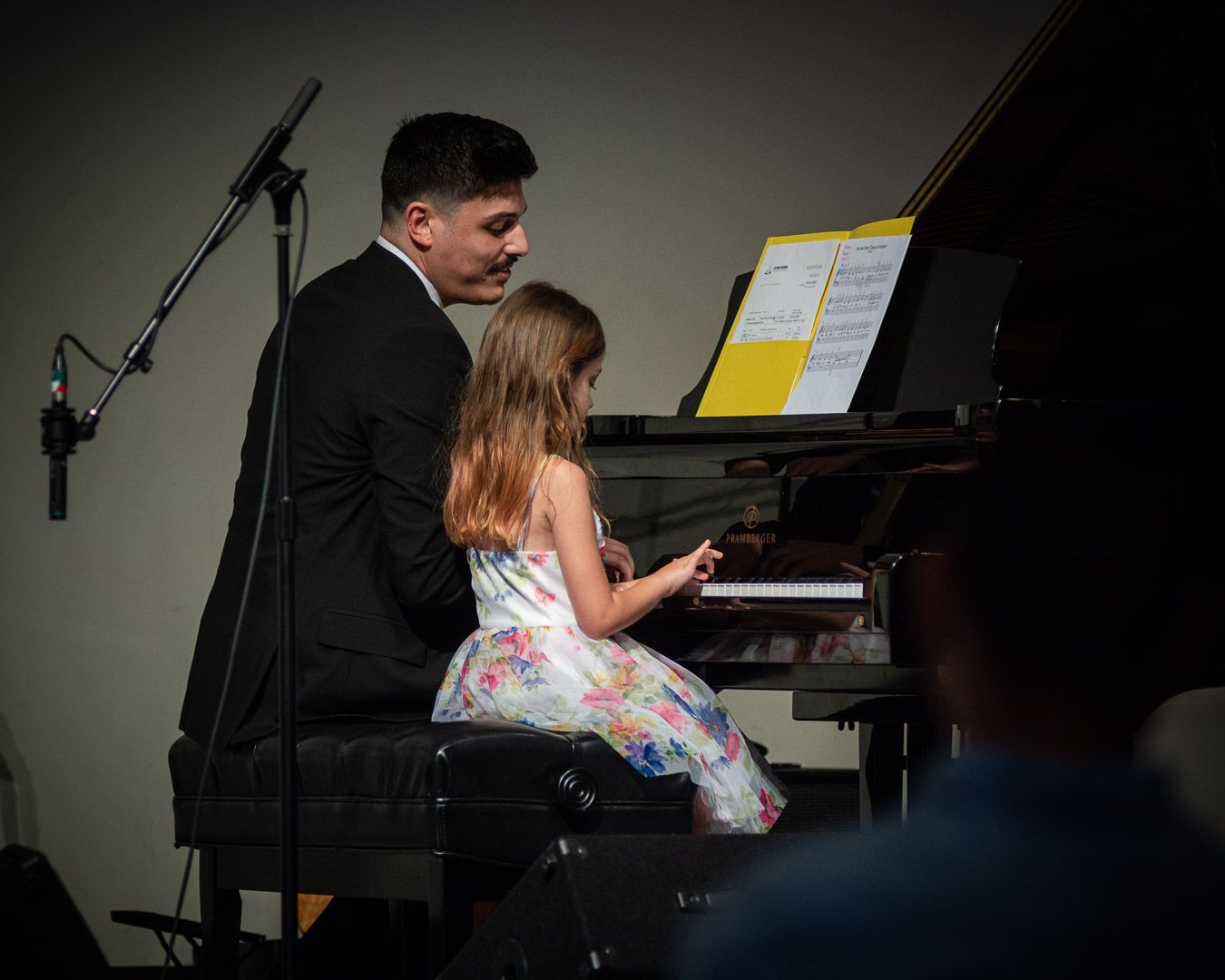 A man is teaching a little girl how to play the piano