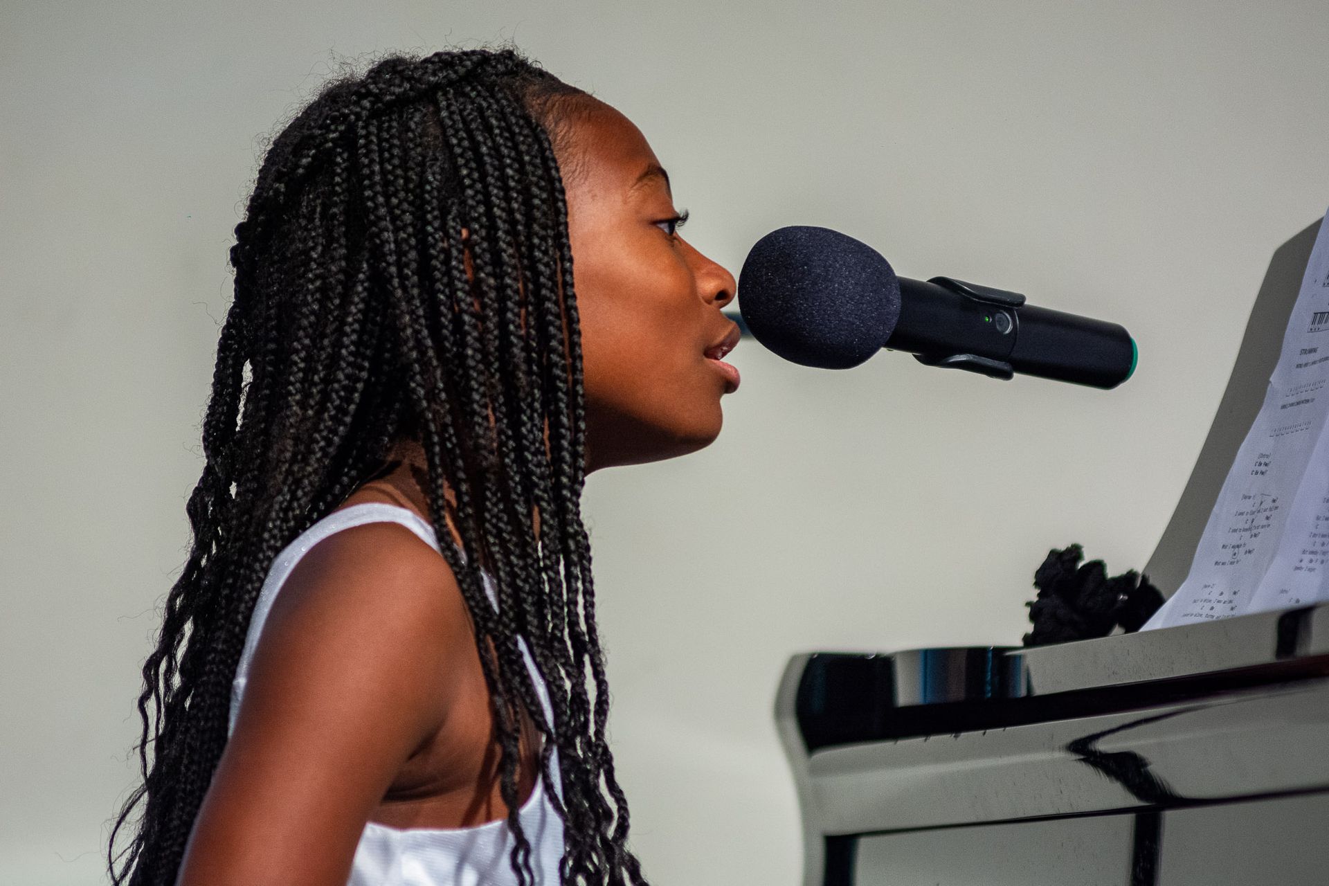 A woman singing into a microphone while playing a piano