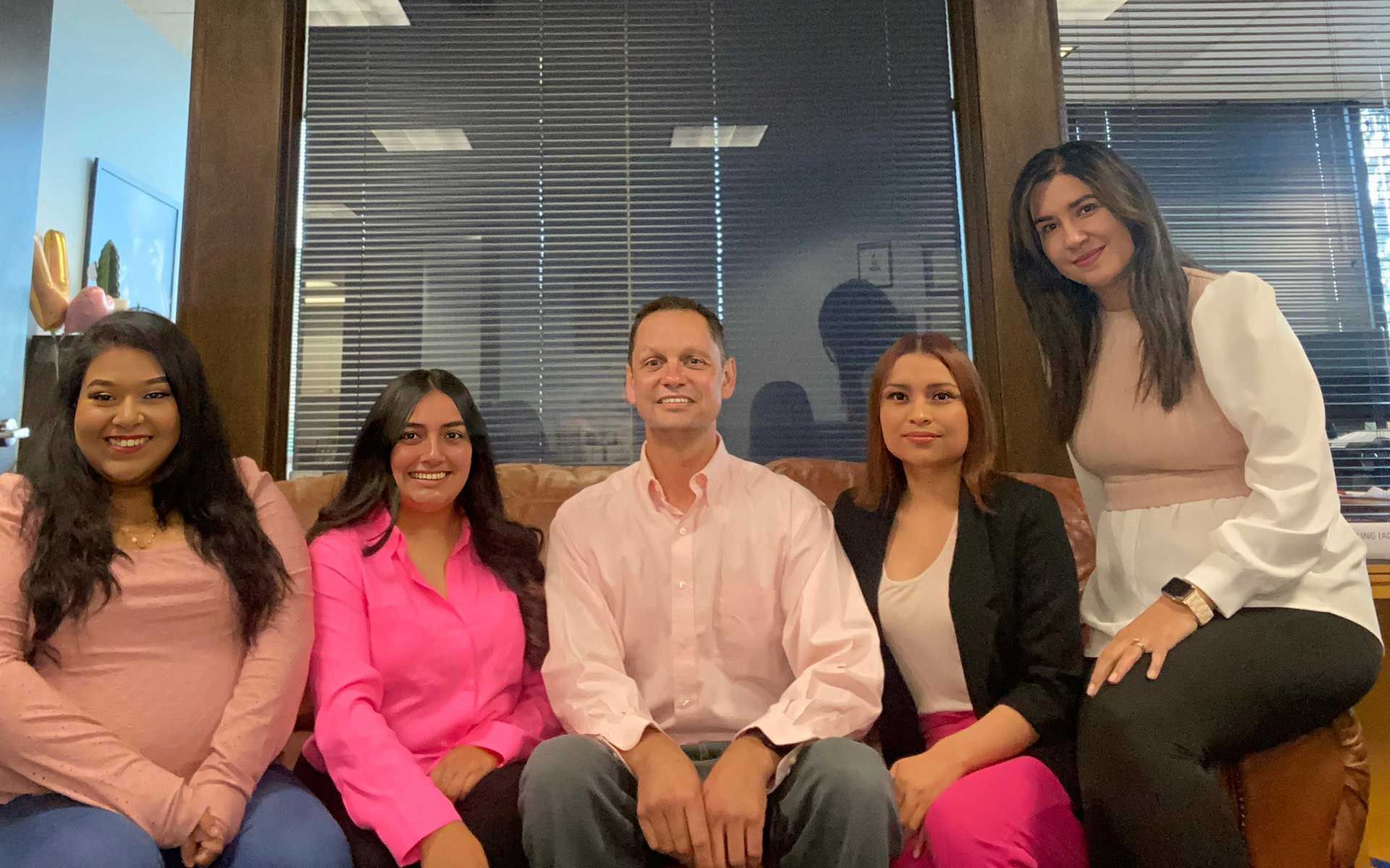 A group of people are posing for a picture while sitting on a couch.