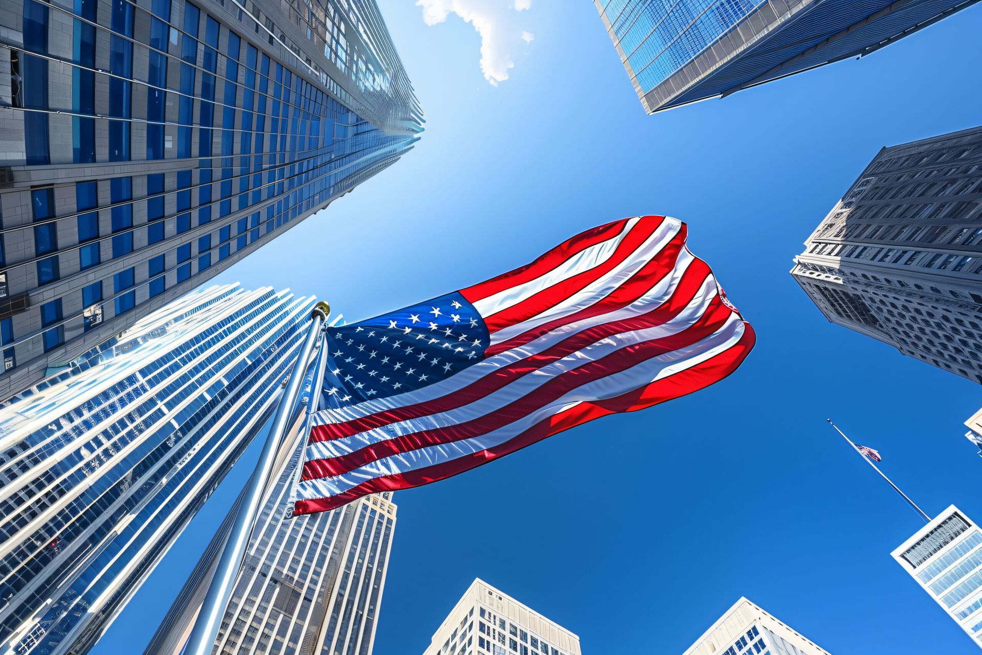 An american flag is waving in the wind between two tall buildings.