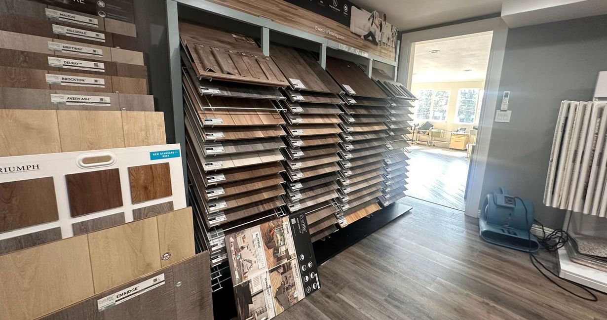 Flooring showroom display with stacked samples in various shades of wood and tile.