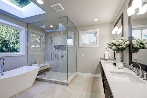 Modern bathroom with a glass-enclosed shower, freestanding tub, double vanity, and a skylight.