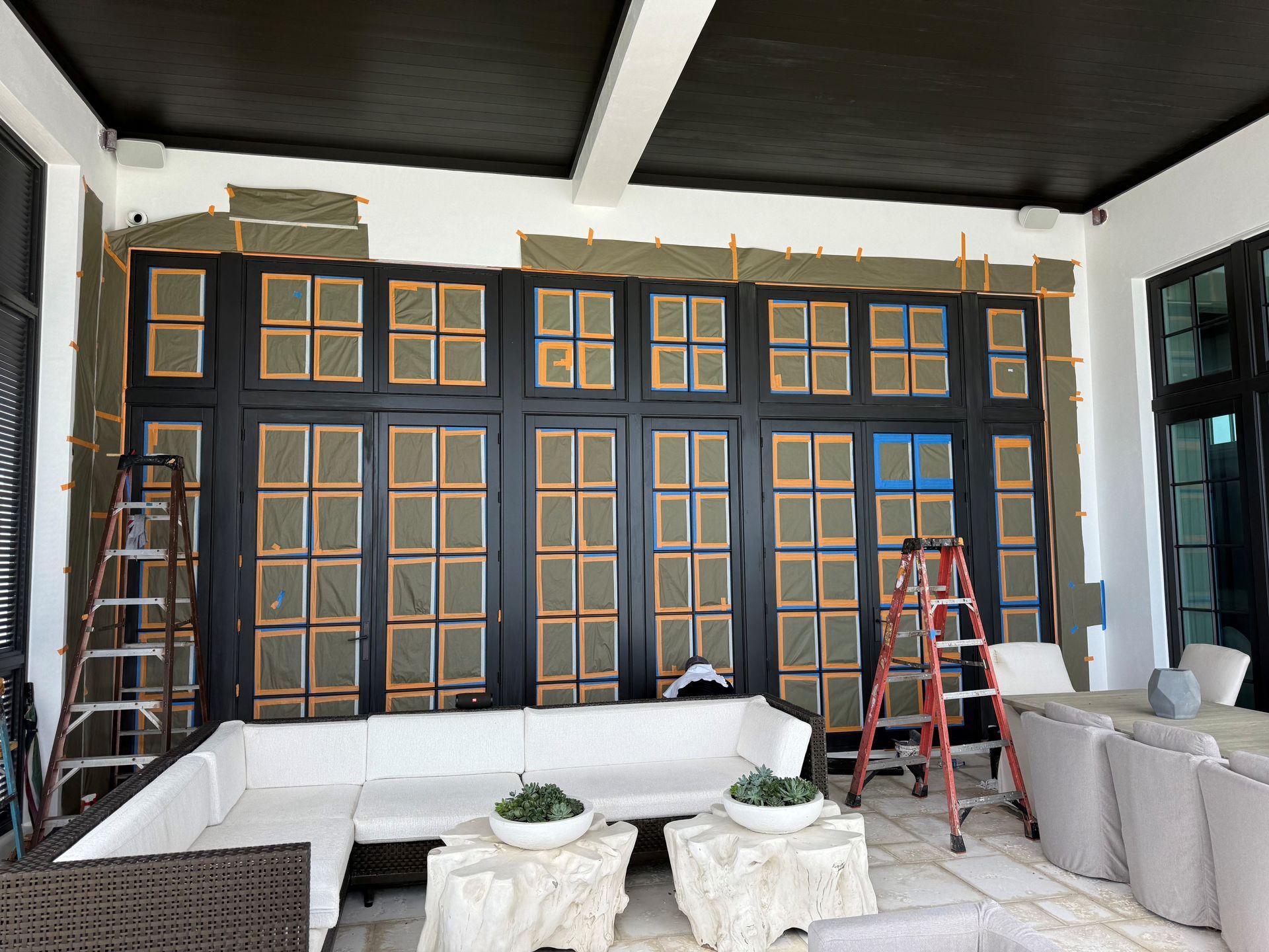 Interior room with black paneled wall, gold trim, ladders, and furniture under renovation
