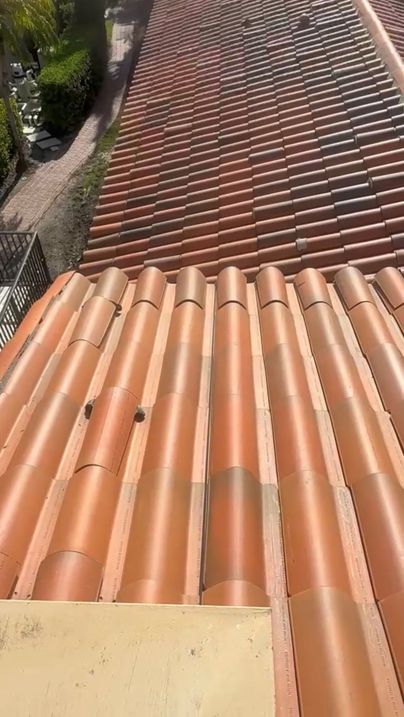 Terracotta tiled roof viewed from above, with rows of curved tiles and a sloped walkway on the left