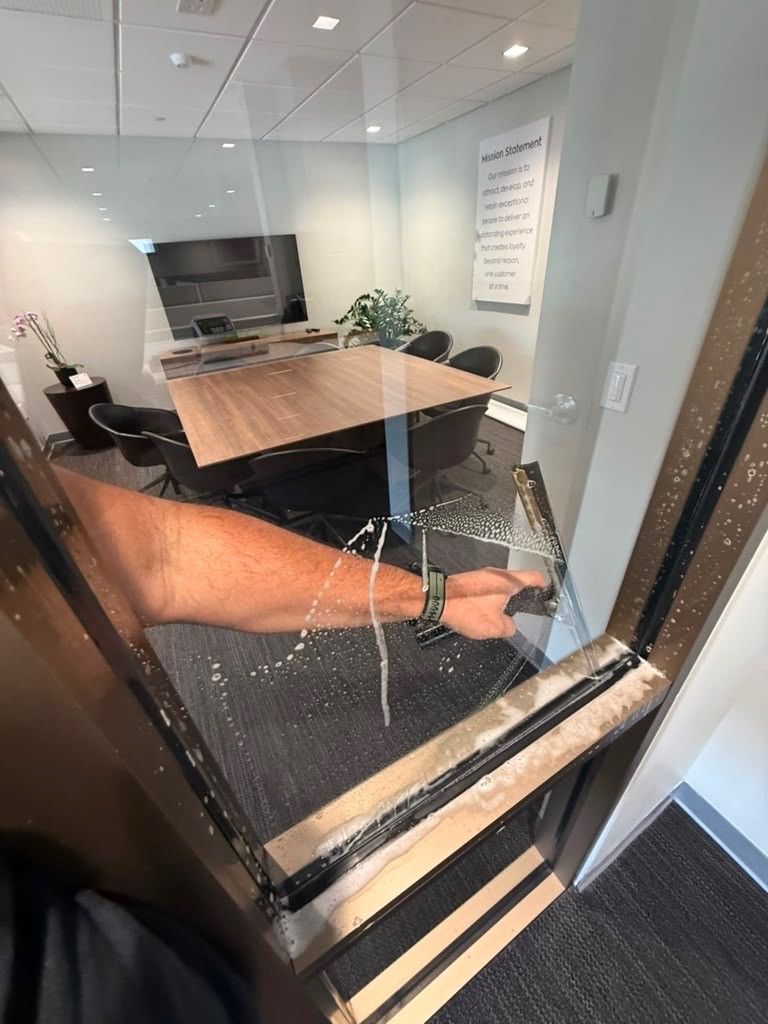 Broken glass on a conference room door, with a meeting table and chairs visible inside.