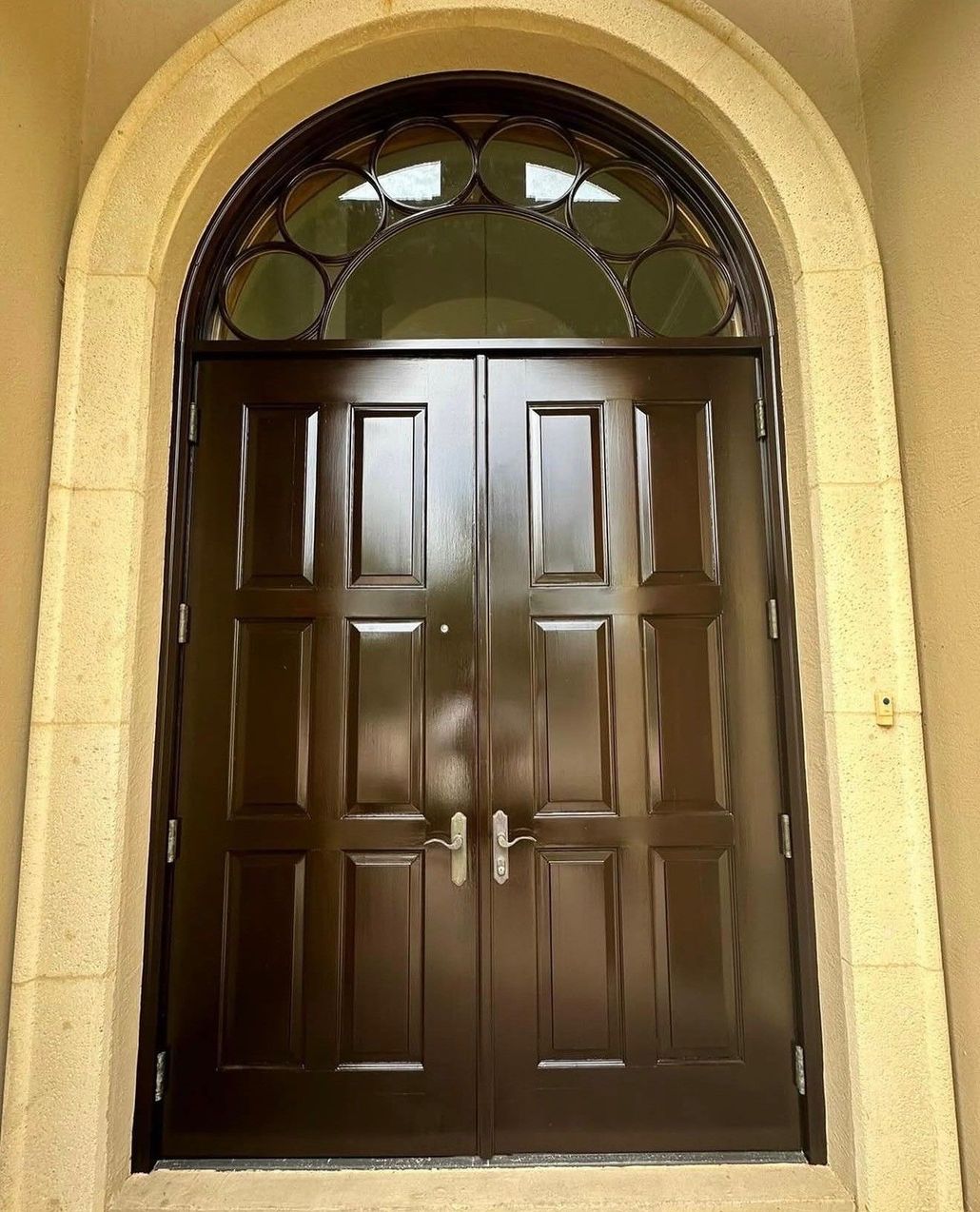 Brown double front door with arched stone frame