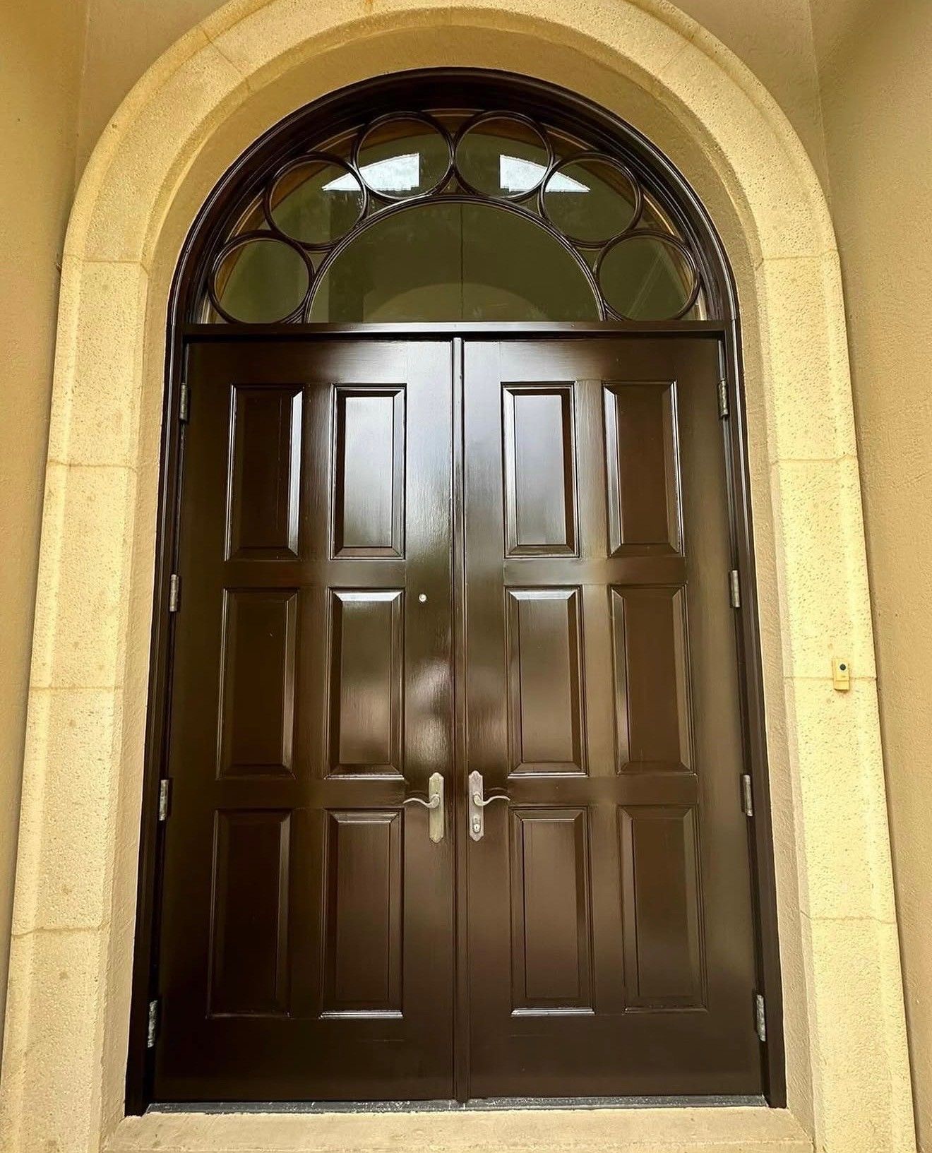 Brown double front door with arched stone frame
