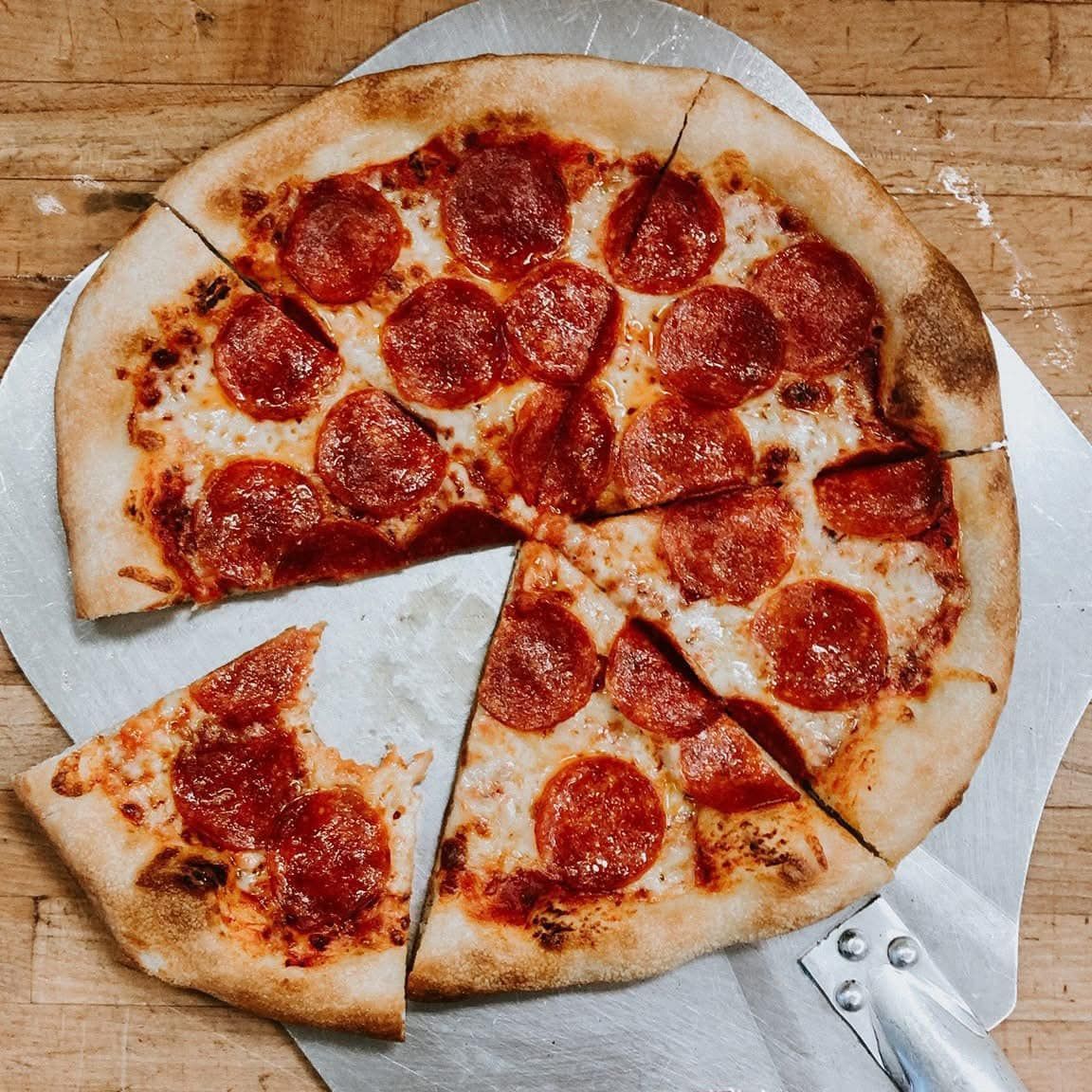 A pepperoni pizza with a slice taken out of it