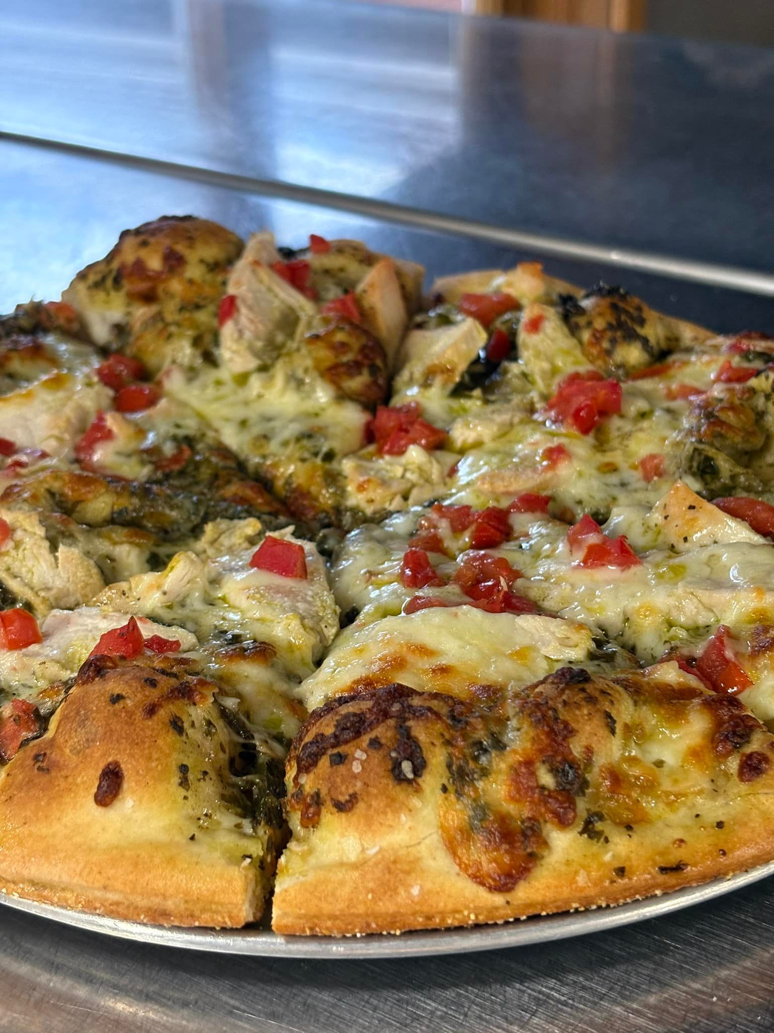 A pizza with a lot of toppings on it is on a plate on a table.