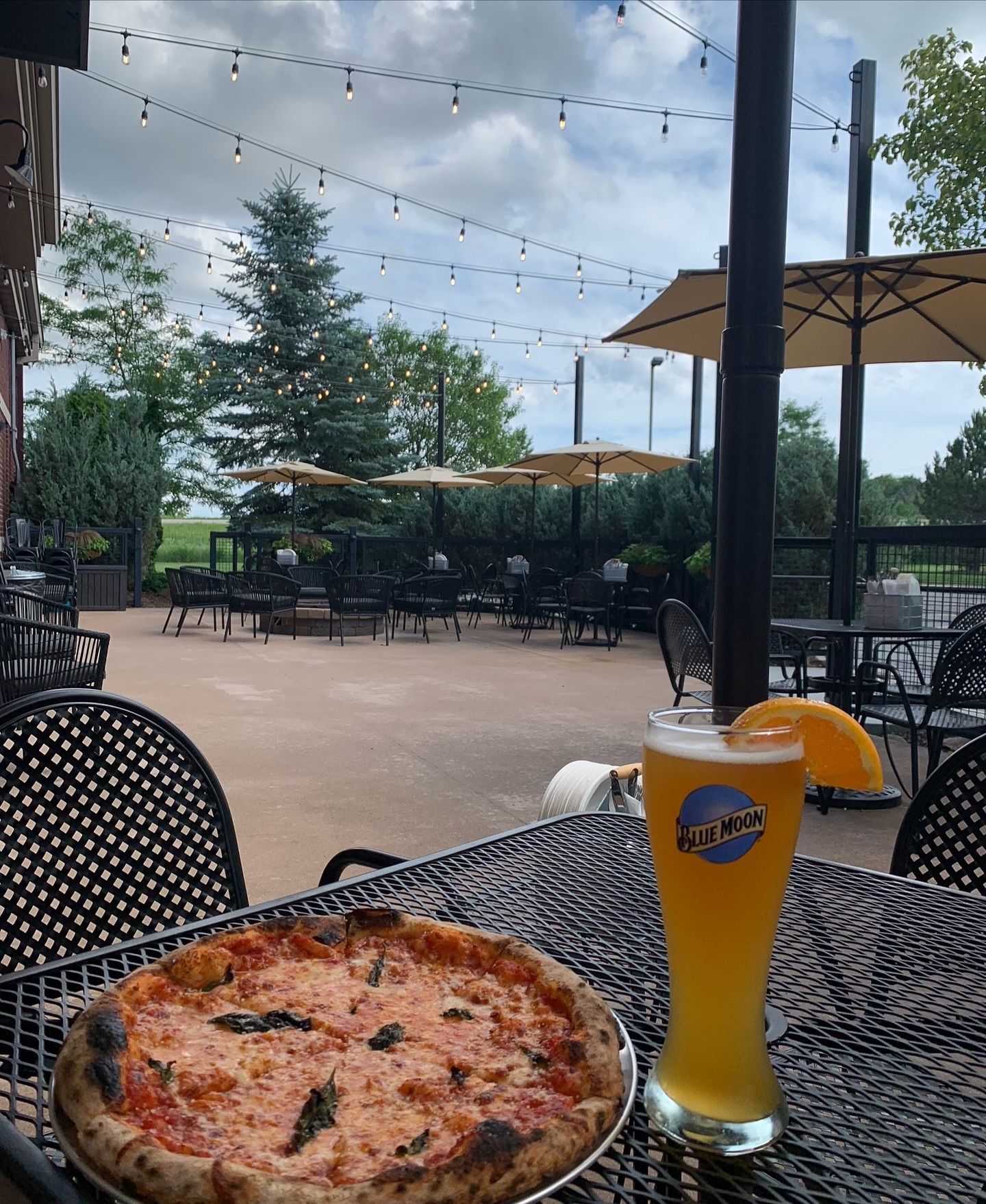 A pizza and a glass of beer on a table outside