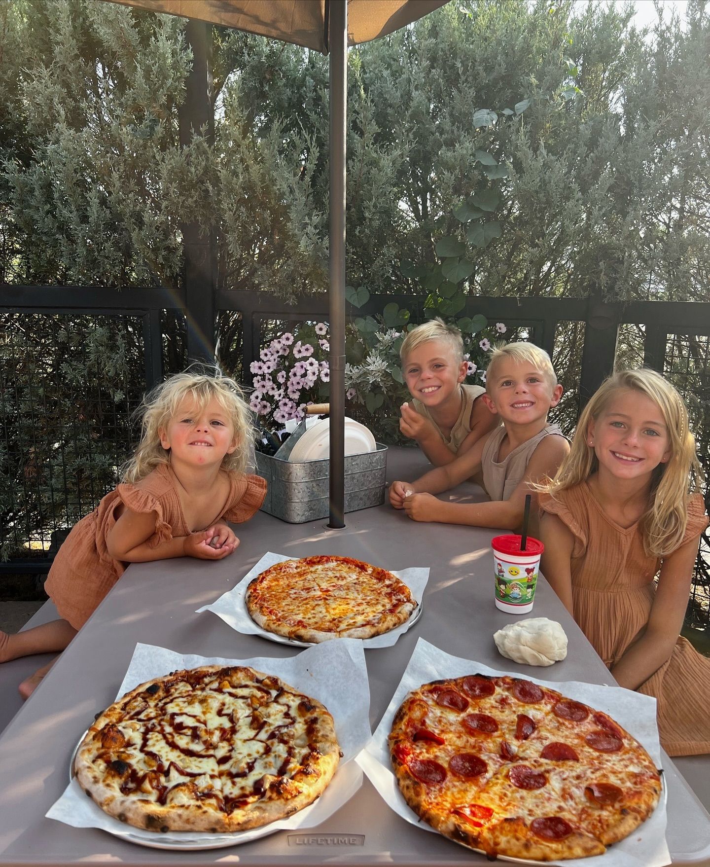 A group of young kids are sitting at a table with pizzas.
