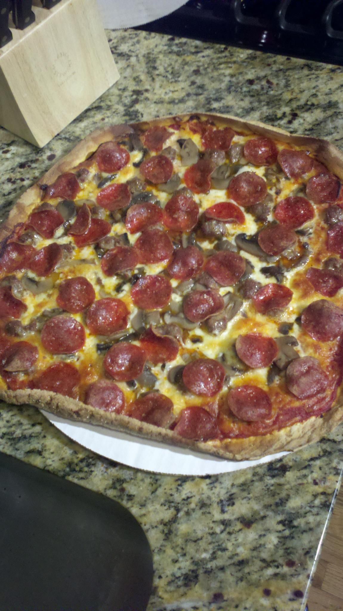 A pepperoni pizza is sitting on a white plate on a counter.