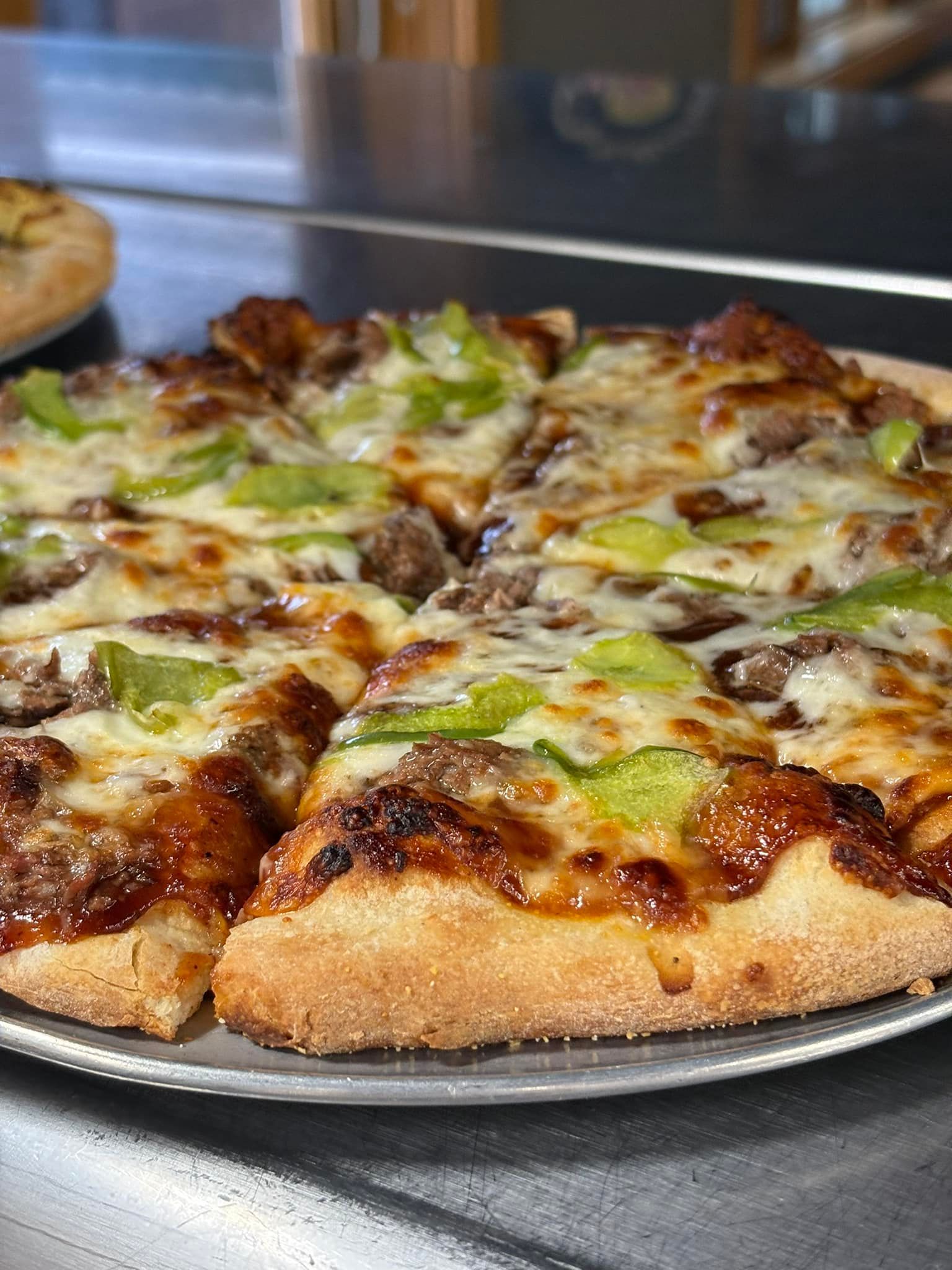 A pizza is sitting on a metal plate on a table.