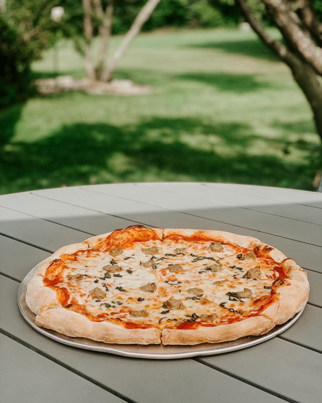 A pizza is sitting on a plate on a table.