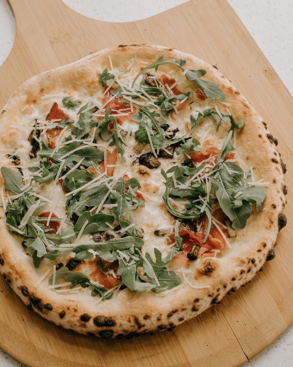 A pizza is sitting on a wooden cutting board.