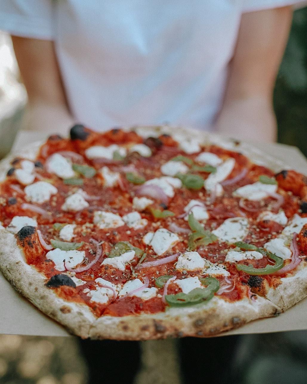 A person is holding a pizza on a piece of paper.