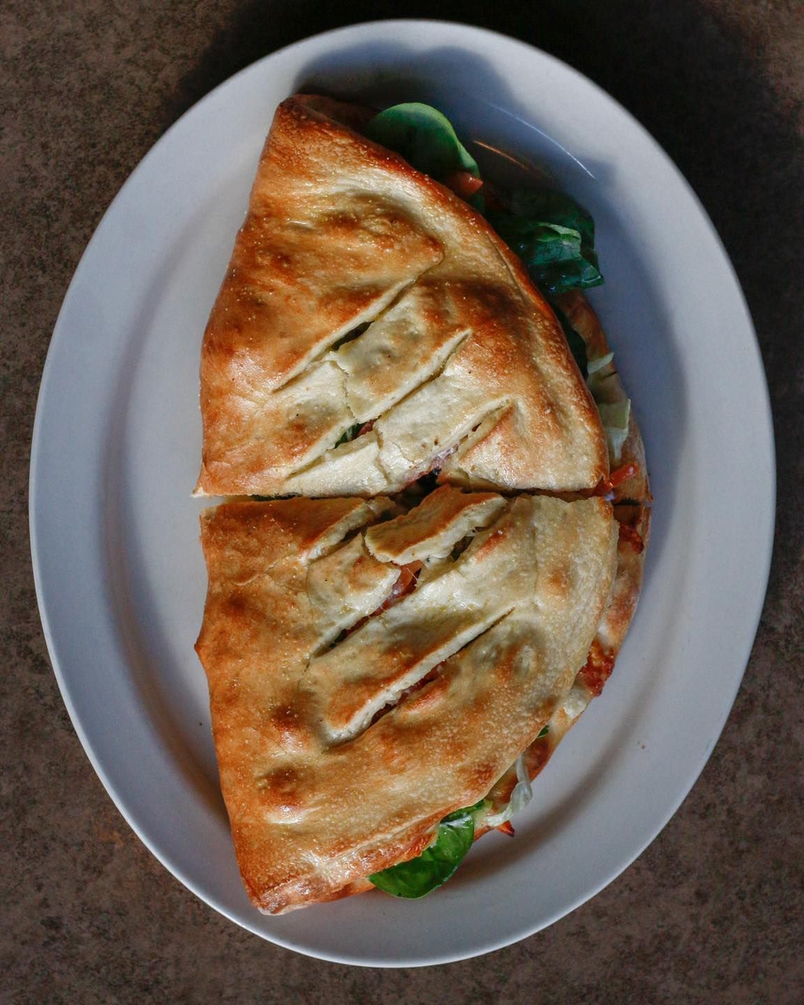 A white plate topped with a sandwich cut in half