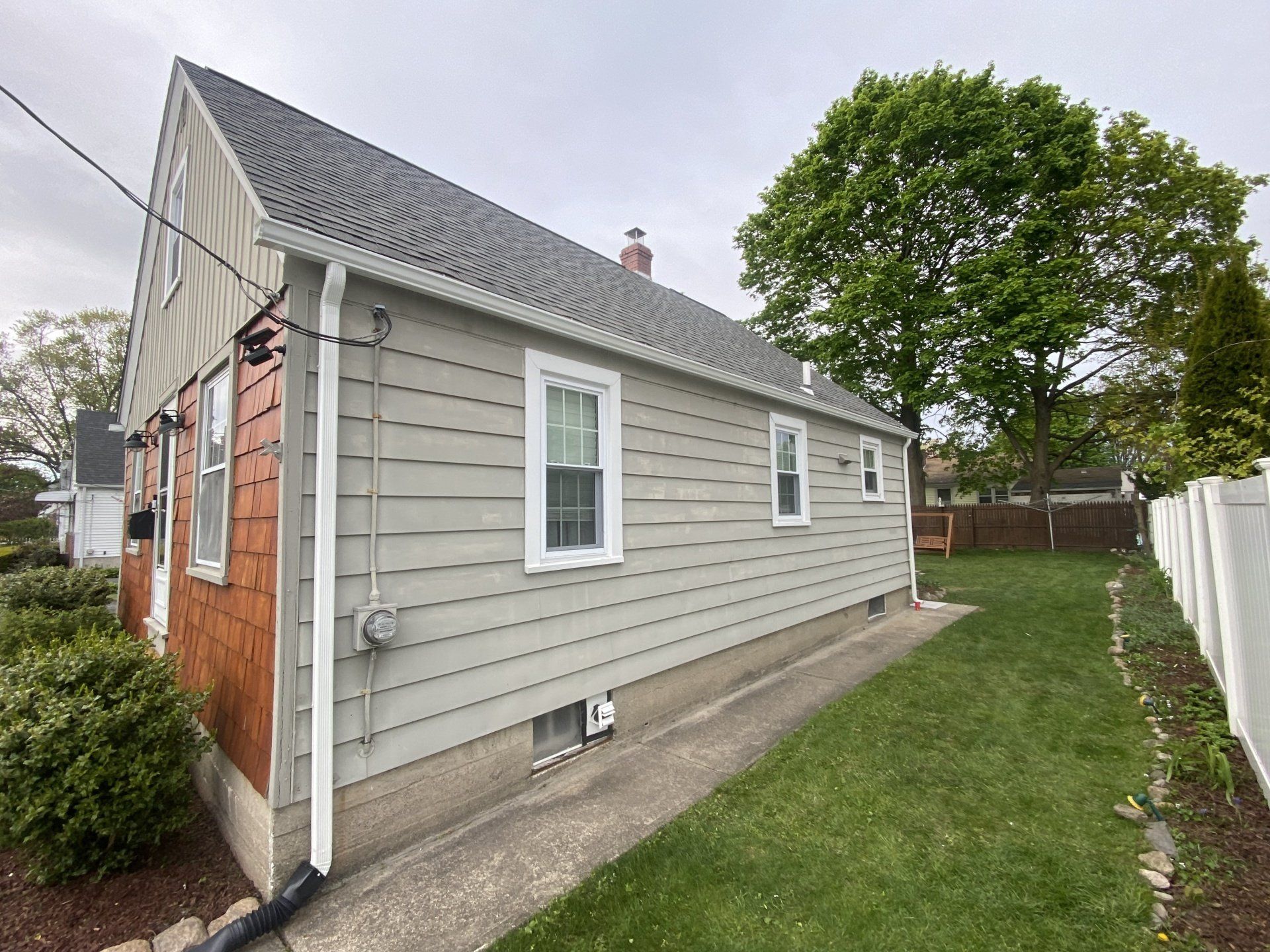 big tree behind light gray house with gray roof