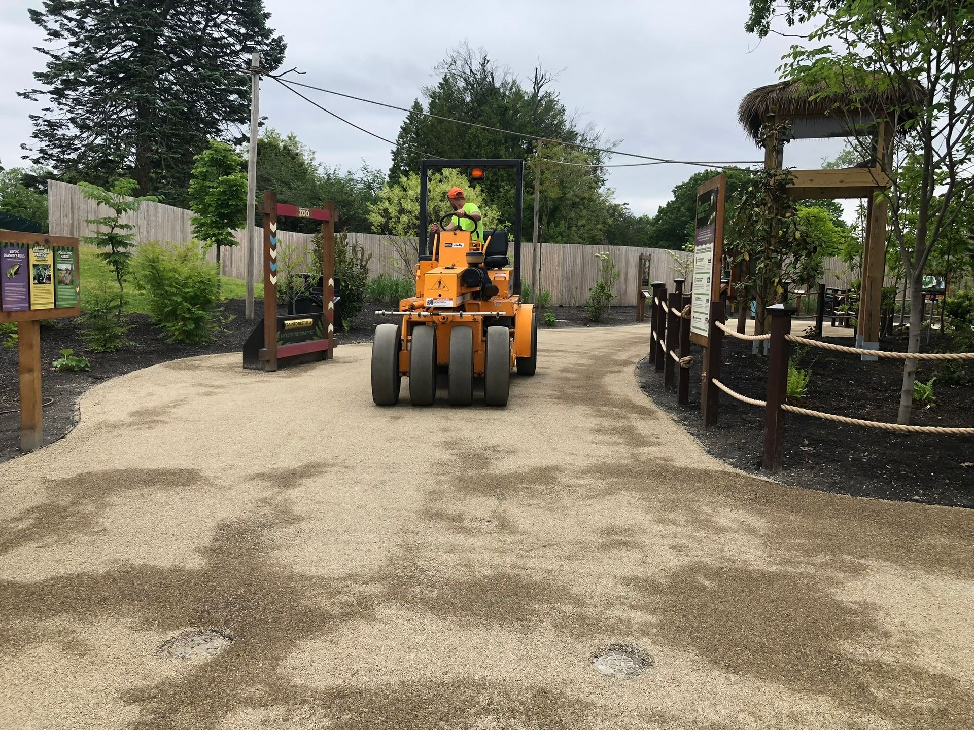 A yellow tractor is driving down a dirt road