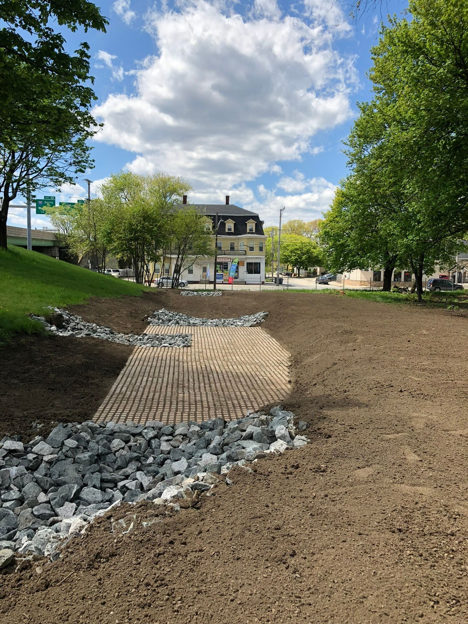 A dirt field with trees and a building in the background