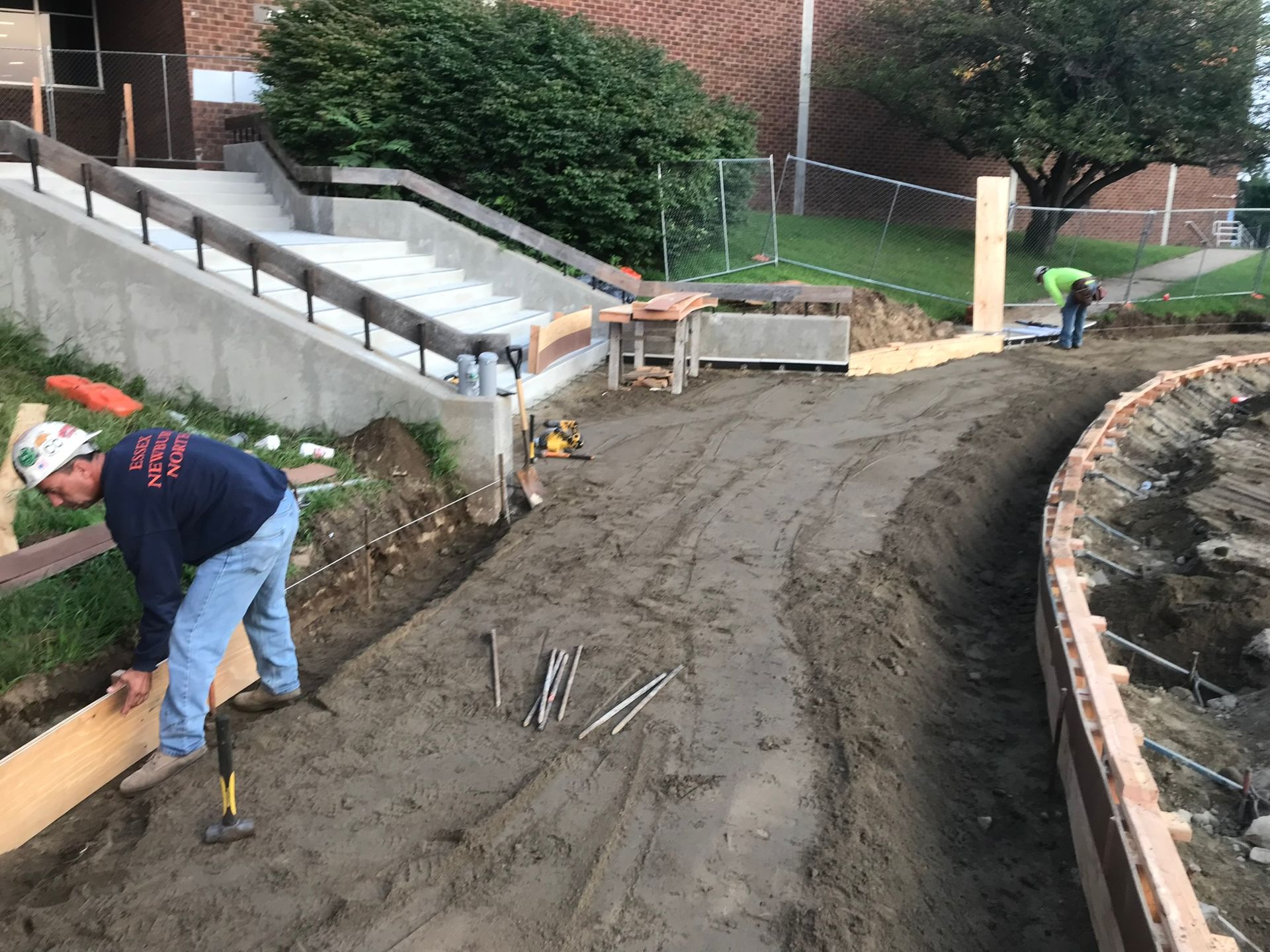 A man is working on a dirt road in front of a building