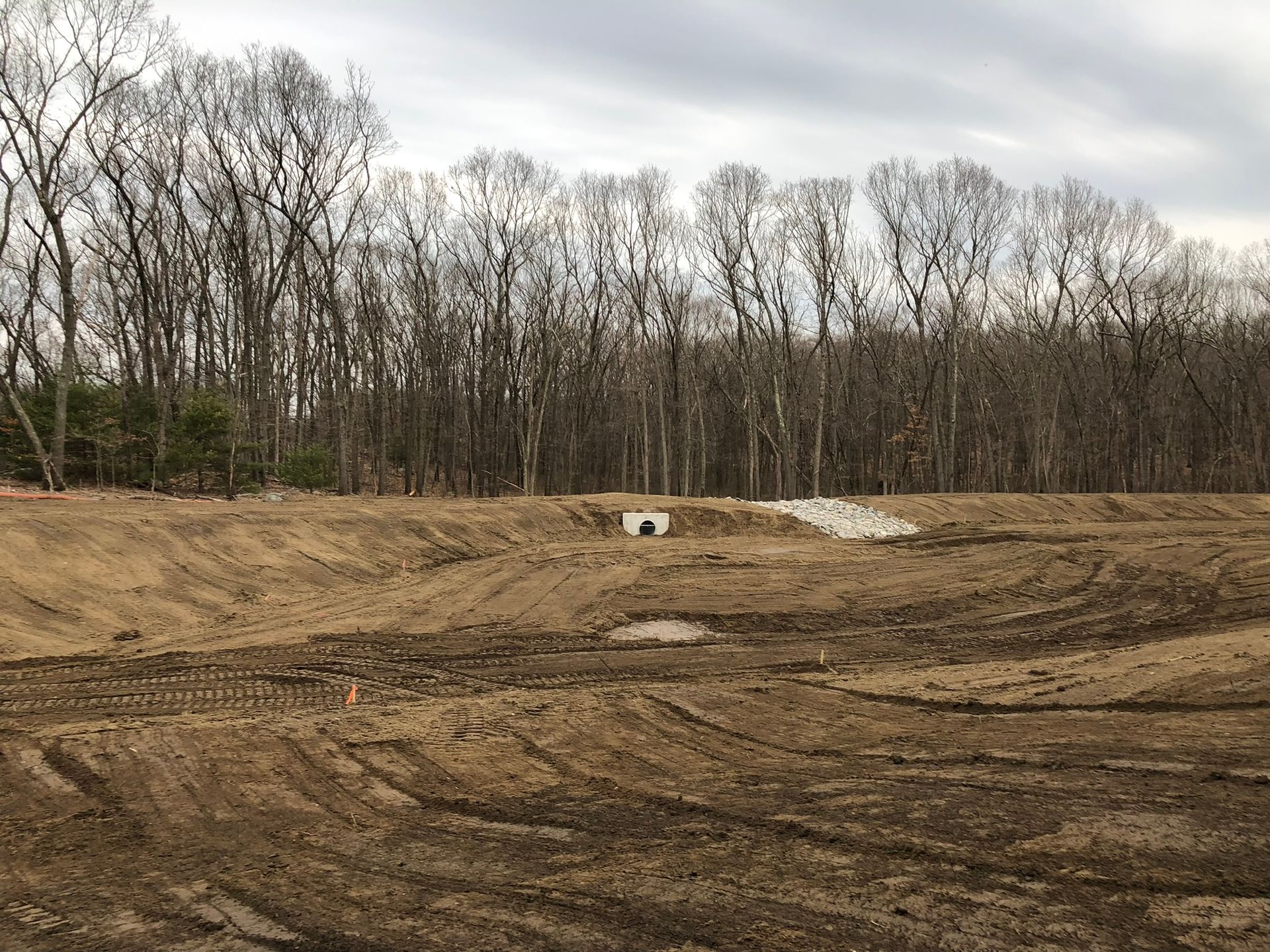 A large dirt field with trees in the background