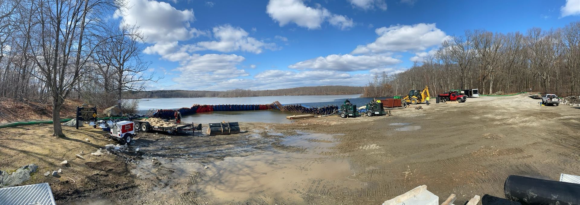 A large body of water is surrounded by trees and a dirt road