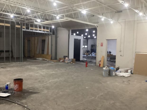 Empty warehouse interior under construction with exposed ceiling, open walls, and scattered tools and materials
