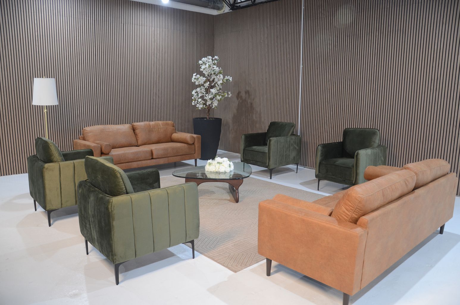Modern living room seating area with green and tan sofas around a coffee table, against patterned walls.