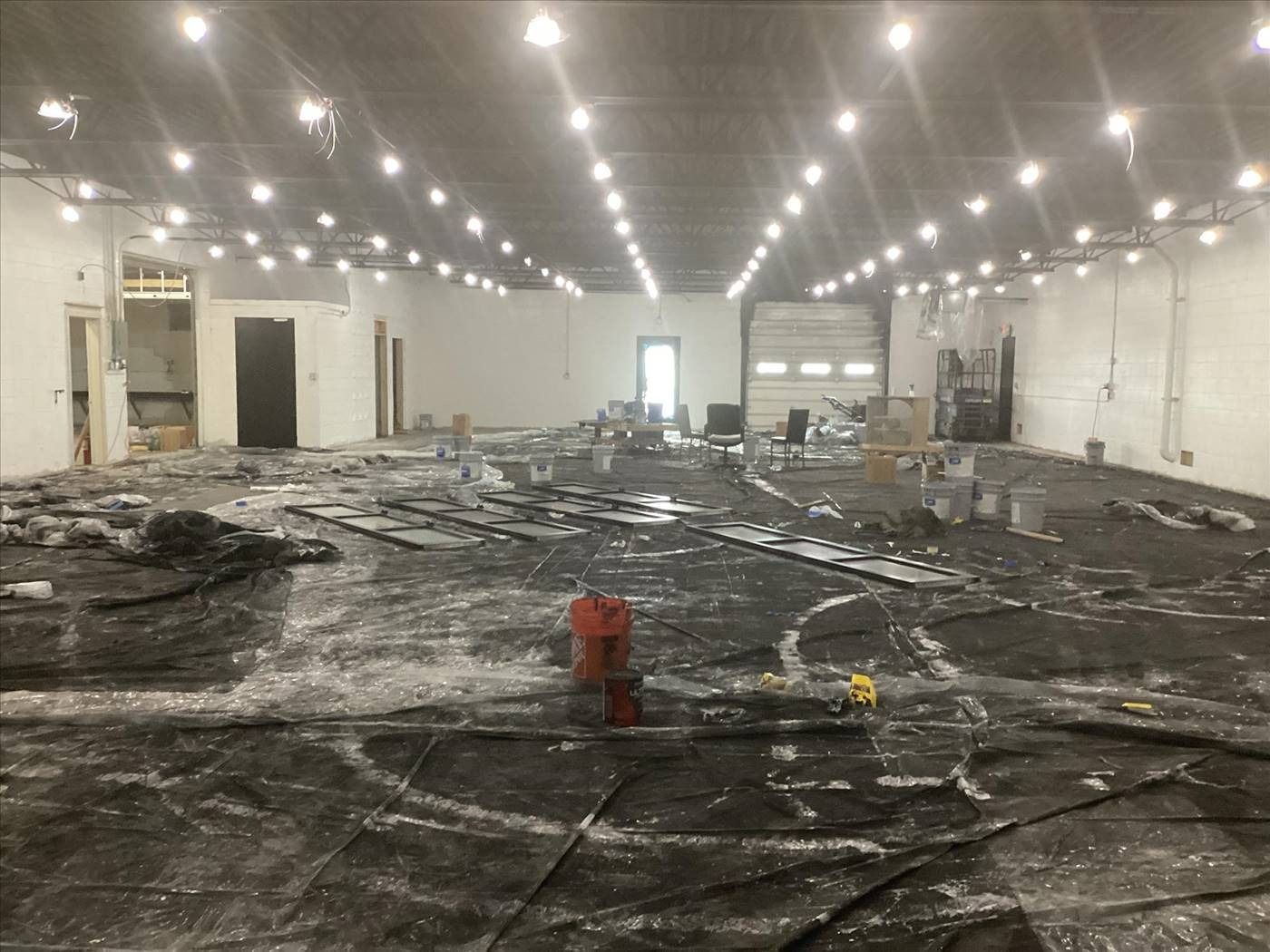 Large warehouse interior with a partially destroyed floor covered in debris and charred material.