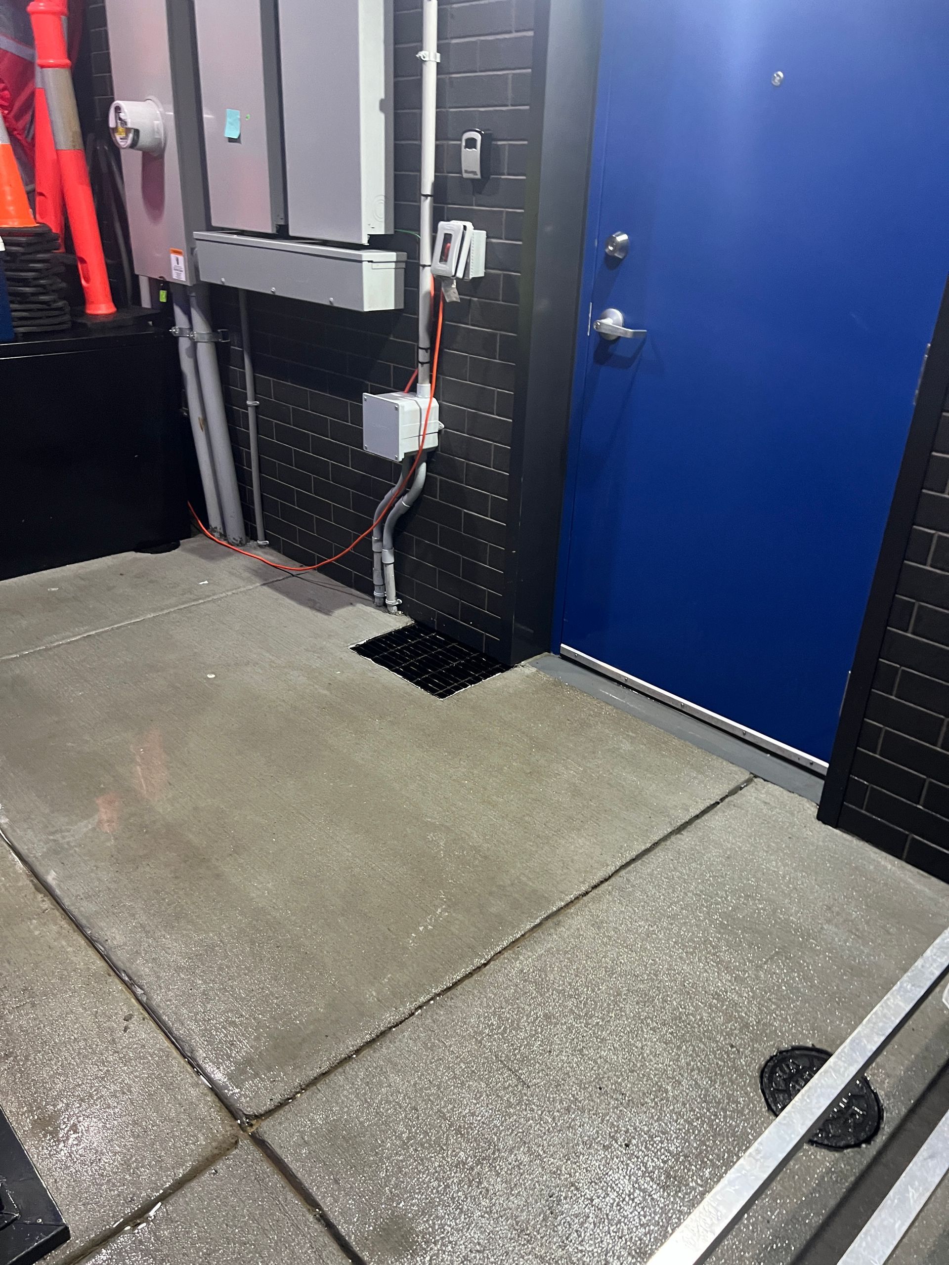 YMCA building with a purple logo on a light-colored exterior wall. A matching wall is in front with a grassy area.