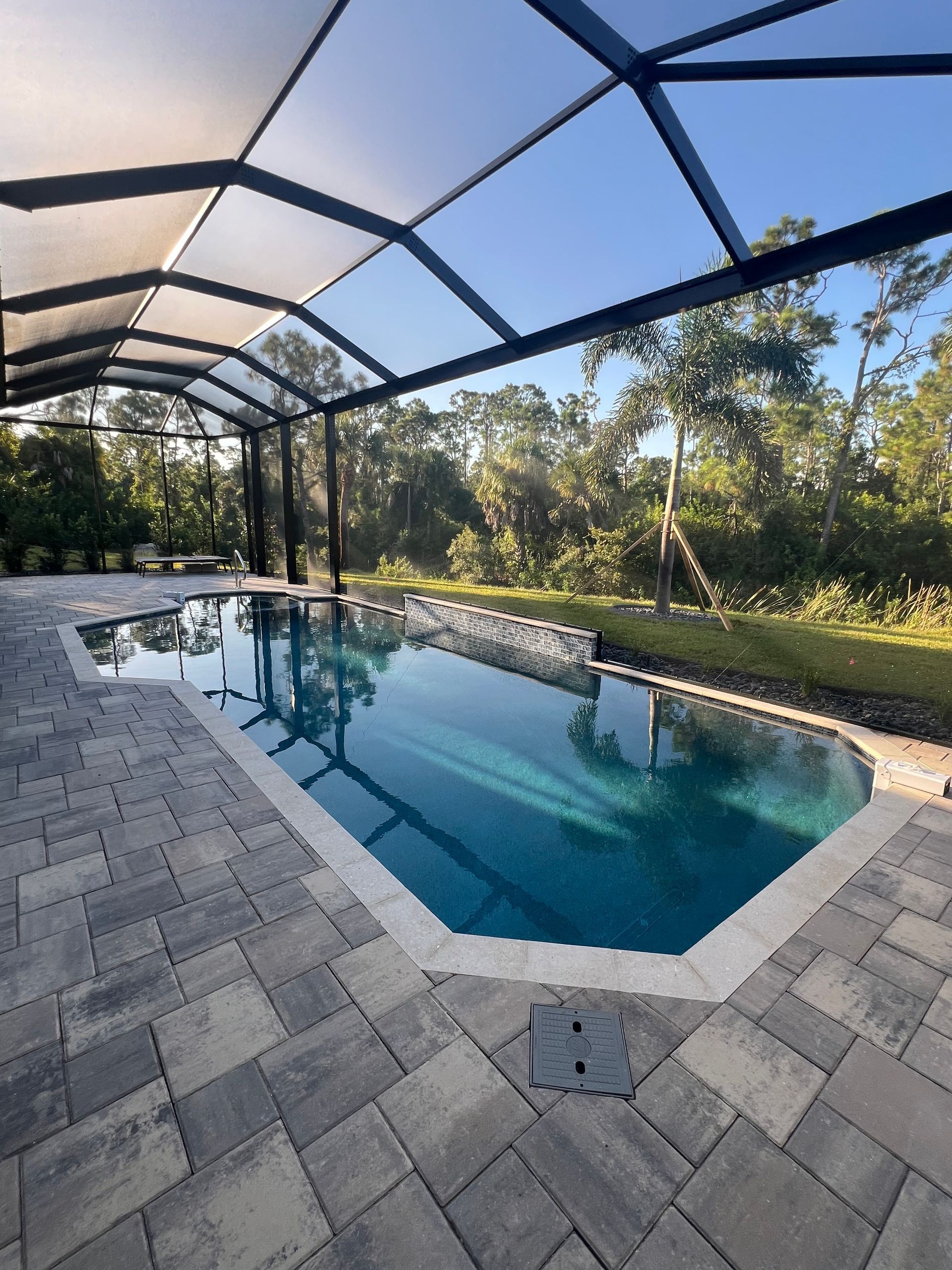 A large swimming pool is surrounded by a screened in area