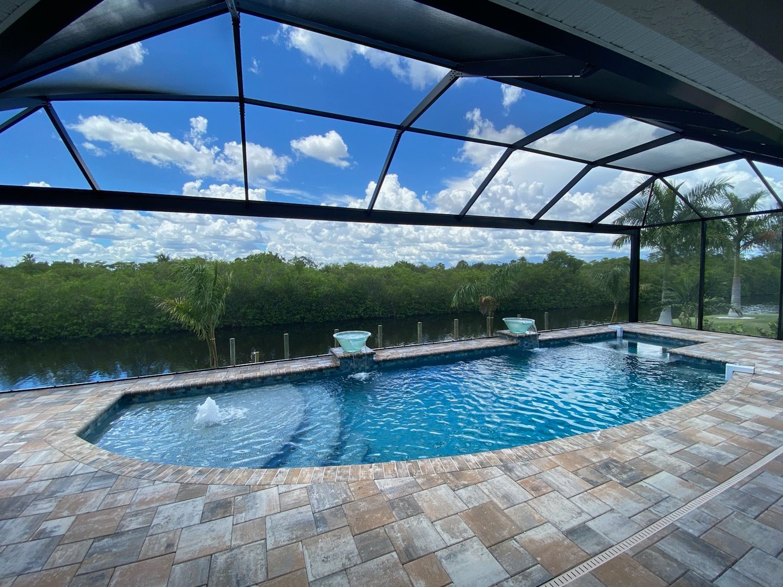 A large swimming pool is surrounded by a screened in area