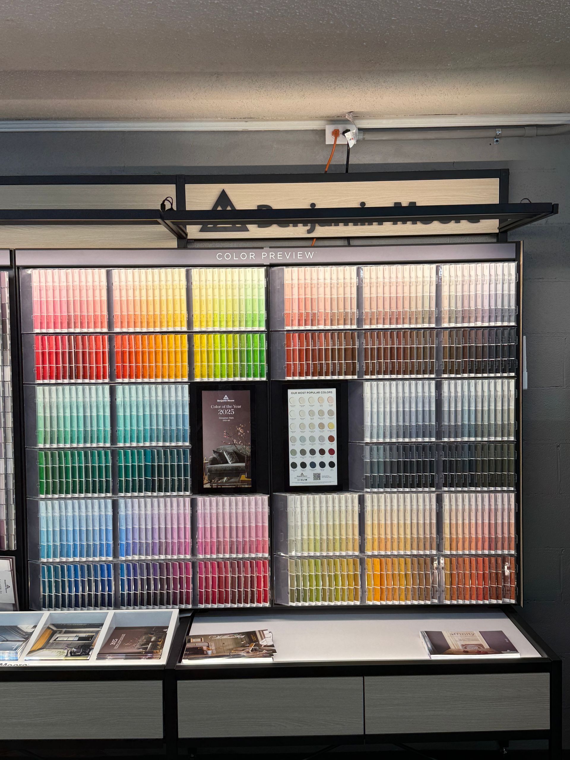 Paint color samples displayed in a store, organized by color. Benjamin Moore logo.