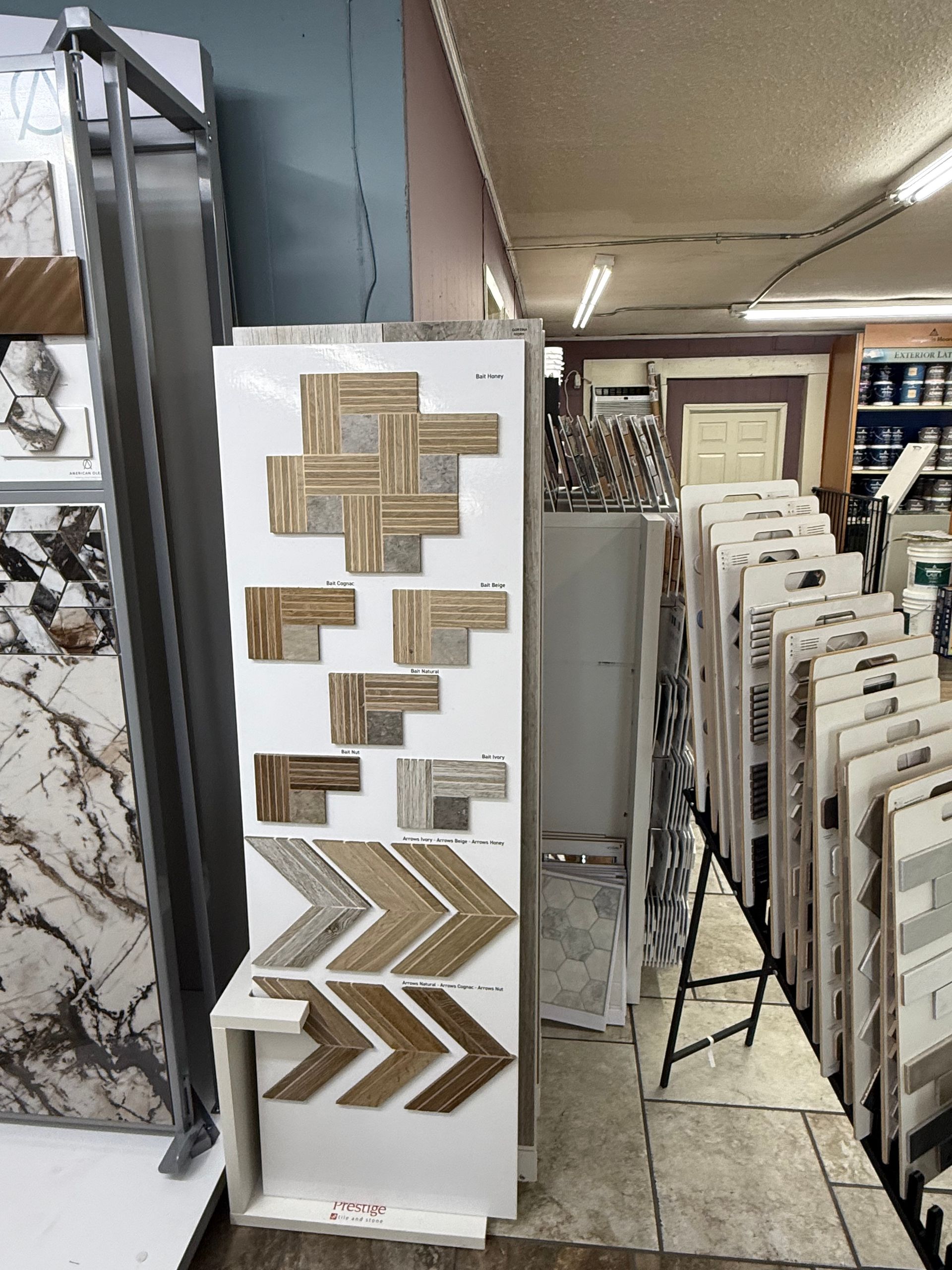 Display of various patterned tiles in a store; brown, white, and gray hues.