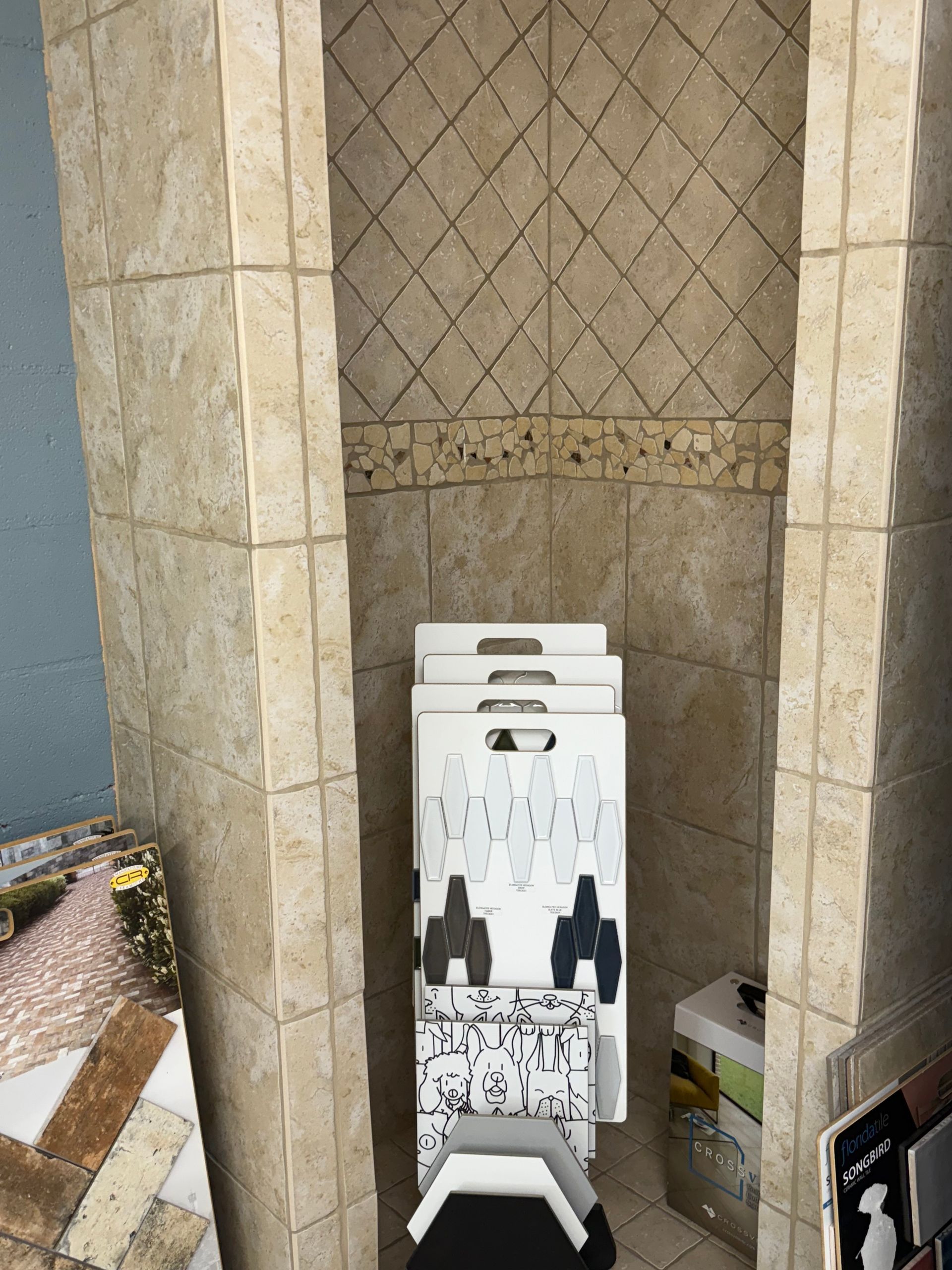 Tile samples inside a tiled alcove with diamond-patterned back wall.