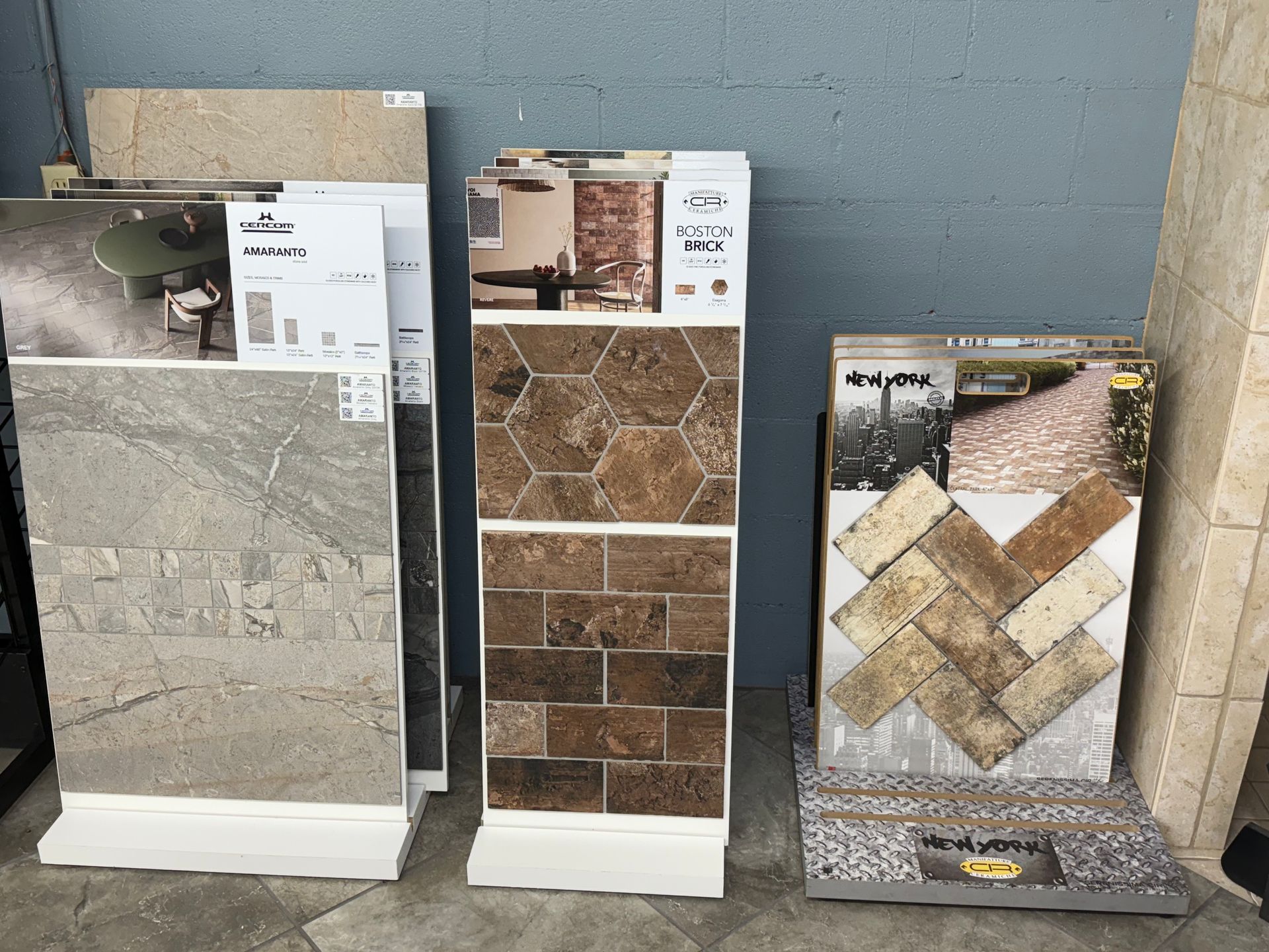 Tile display showcasing various patterns and colors, including stone, brick, and herringbone.