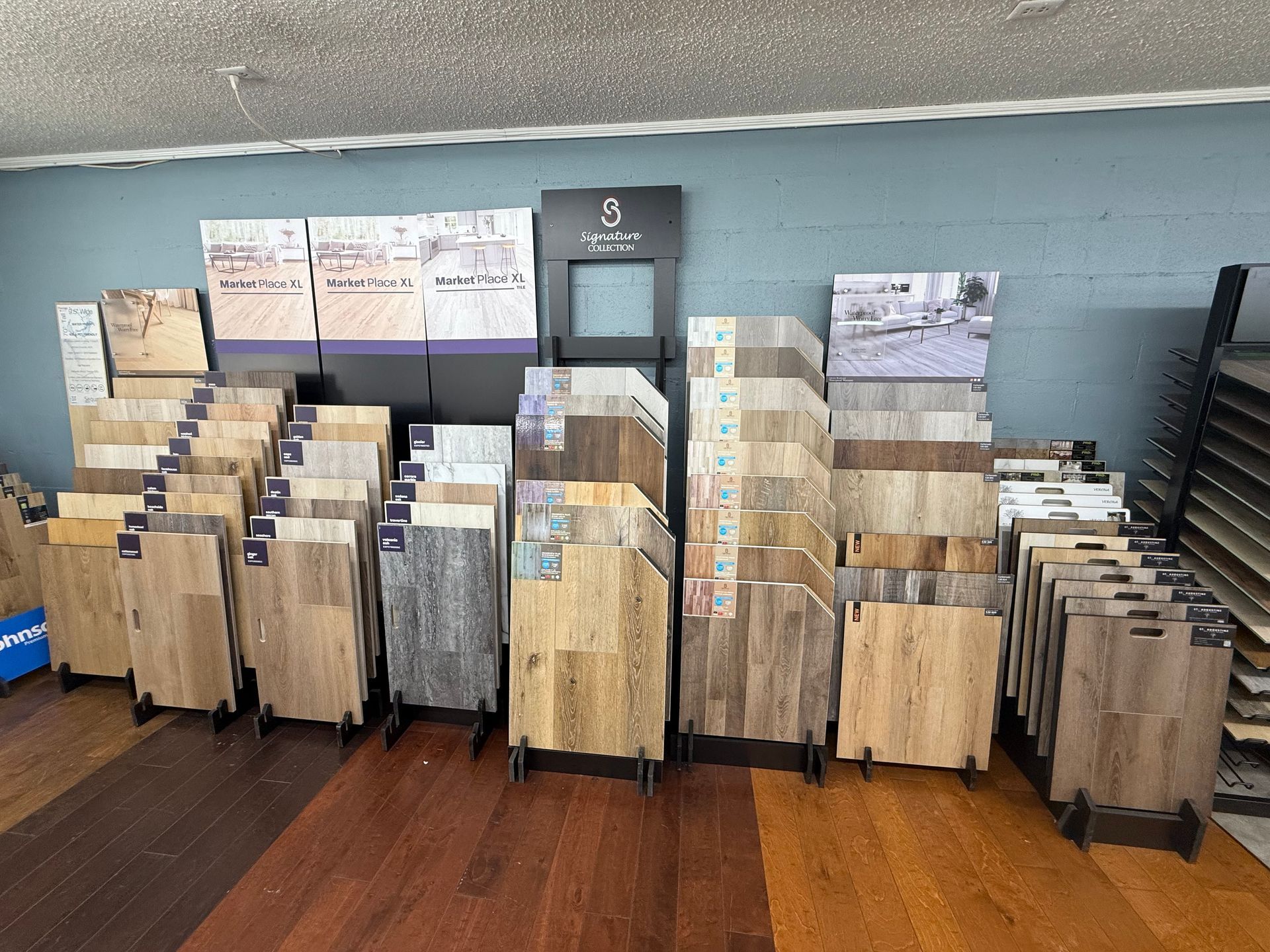 Display of wood flooring samples in a showroom, various colors and styles arranged on stands.