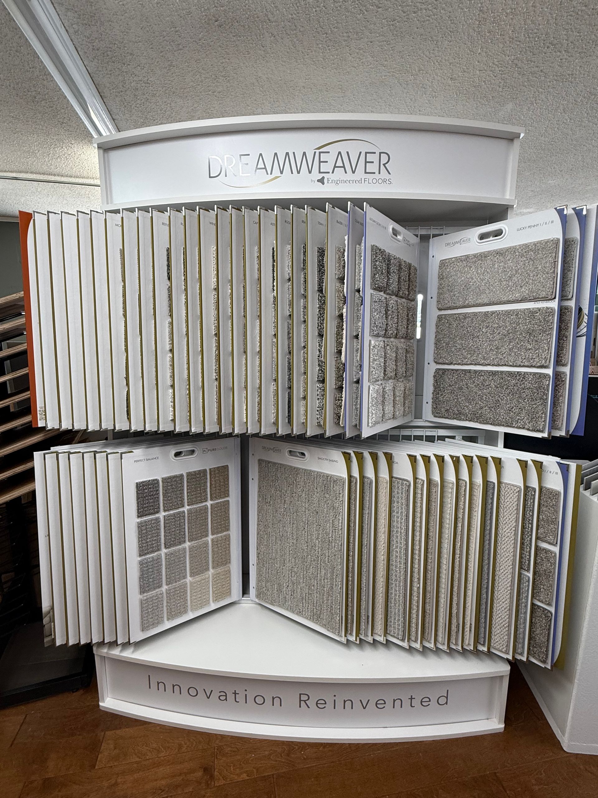 Rotating display of carpet samples in various neutral colors at a flooring store.
