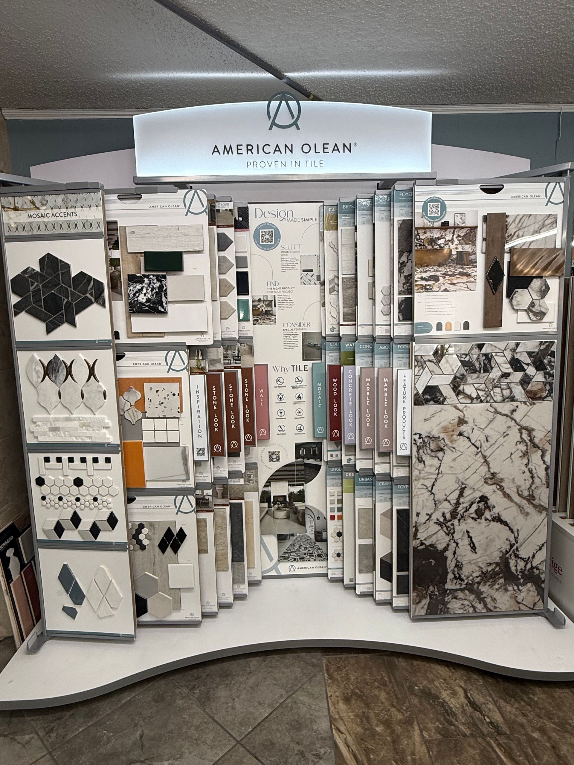 Display of American Olean tile samples, showcasing various colors, patterns, and textures in a retail setting.