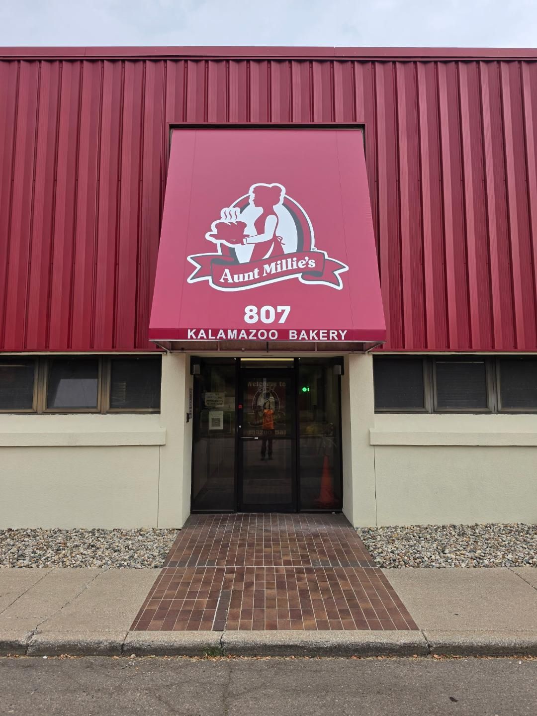 Red storefront of a bakery with a maroon sign, glass entrance, and brick walkway, numbered 807.
