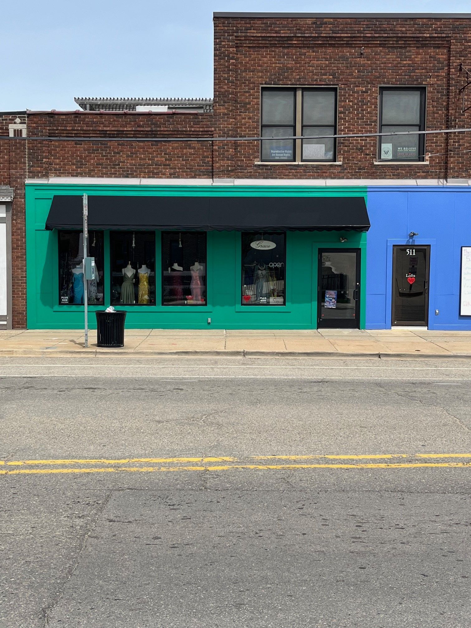 Teal storefront with brick facade and large windows on a quiet street.